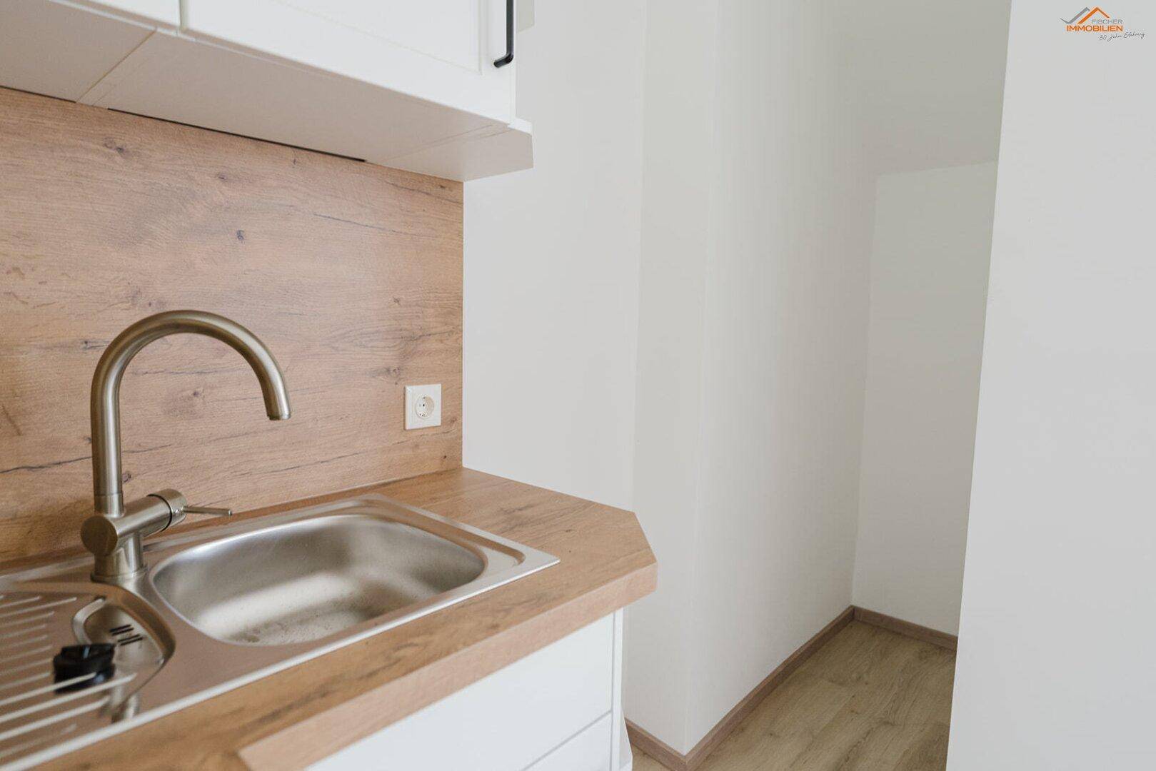 Detailansicht der Küchenspüle mit modernem Wasserhahn und Holzarbeitsplatte.