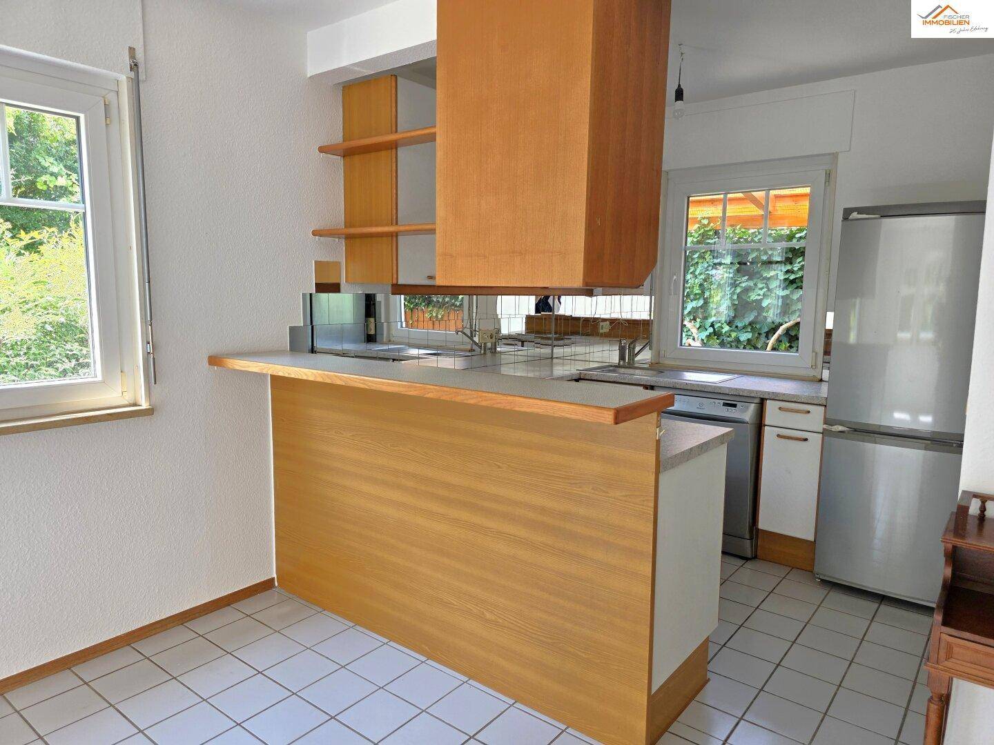 Küche mit Holzfronten, Frühstücksbar und Blick ins Grüne durch das Fenster.