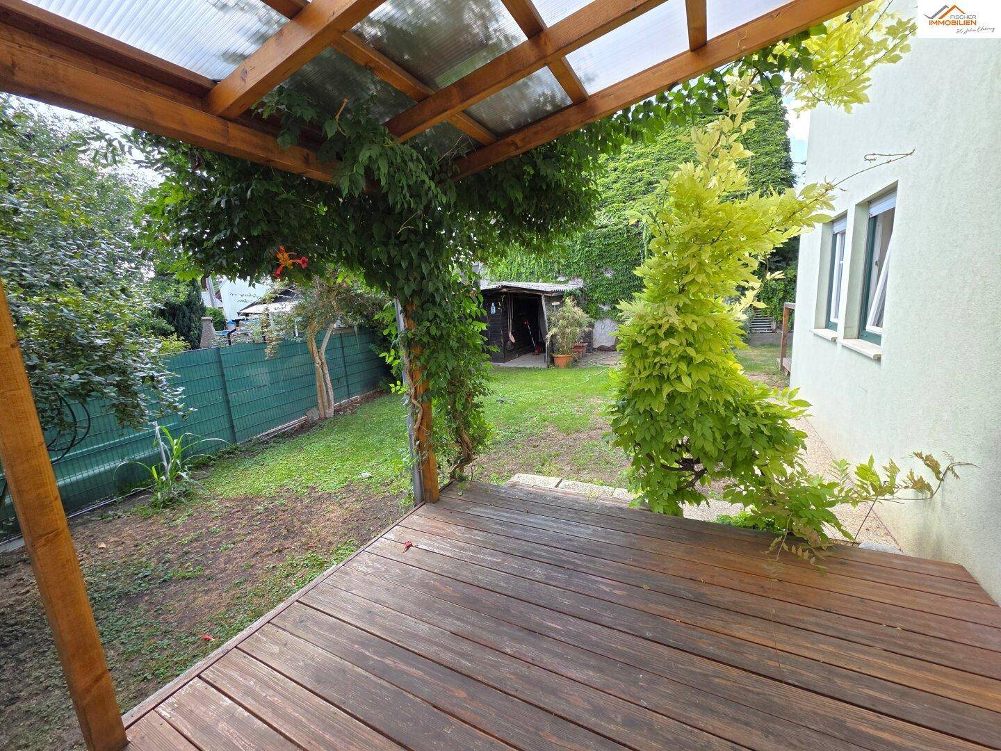 Überdachte Holzterrasse mit Blick auf den Garten und üppige Kletterpflanzen.
