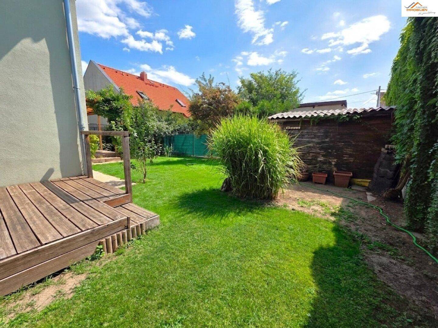 Weitläufiger Gartenbereich mit grünem Rasen, einem Gartenhaus und üppiger Vegetation.