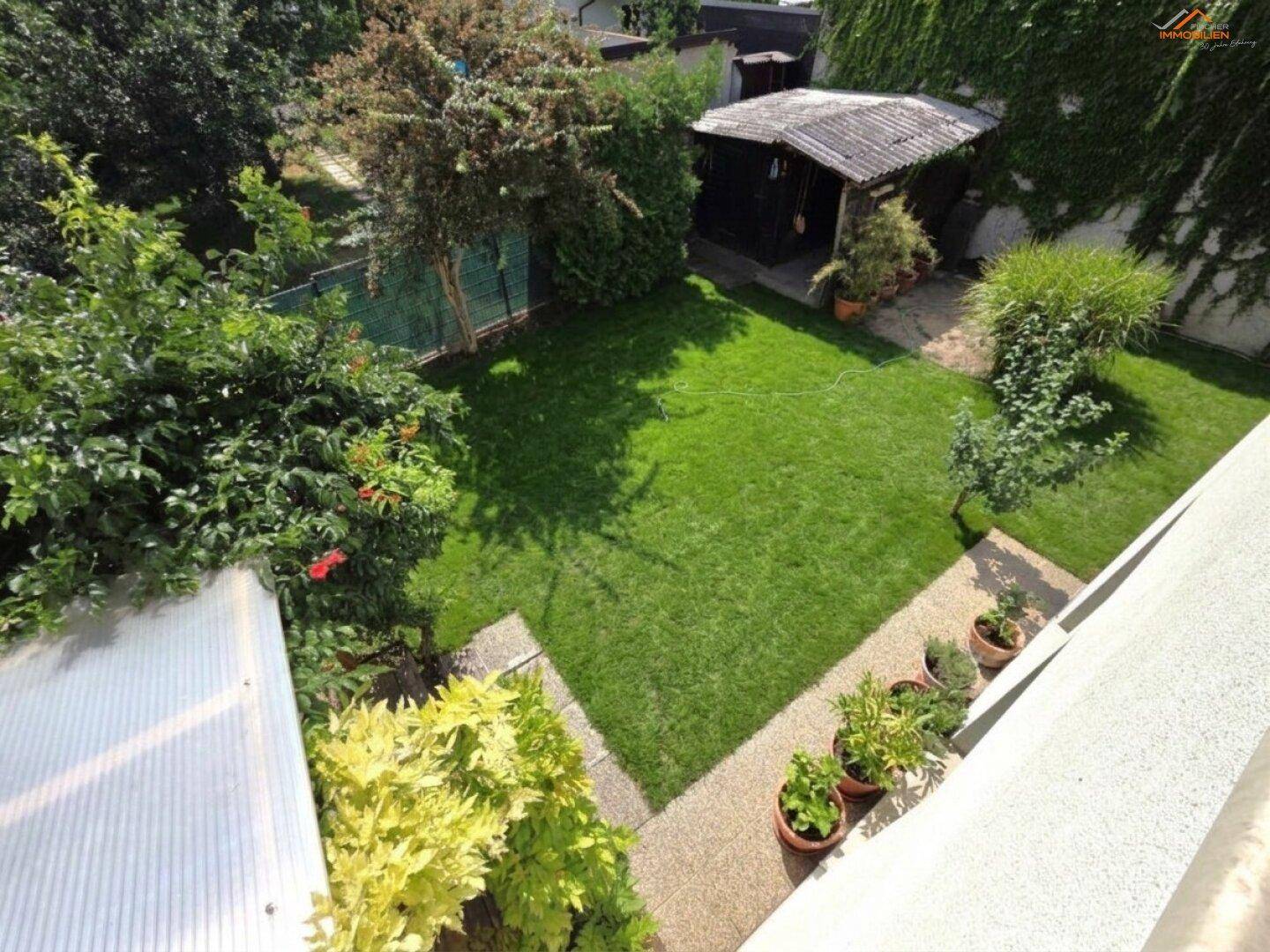 Vogelperspektive auf den gepflegten Garten mit Rasenfläche und verschiedenen Pflanzen.
