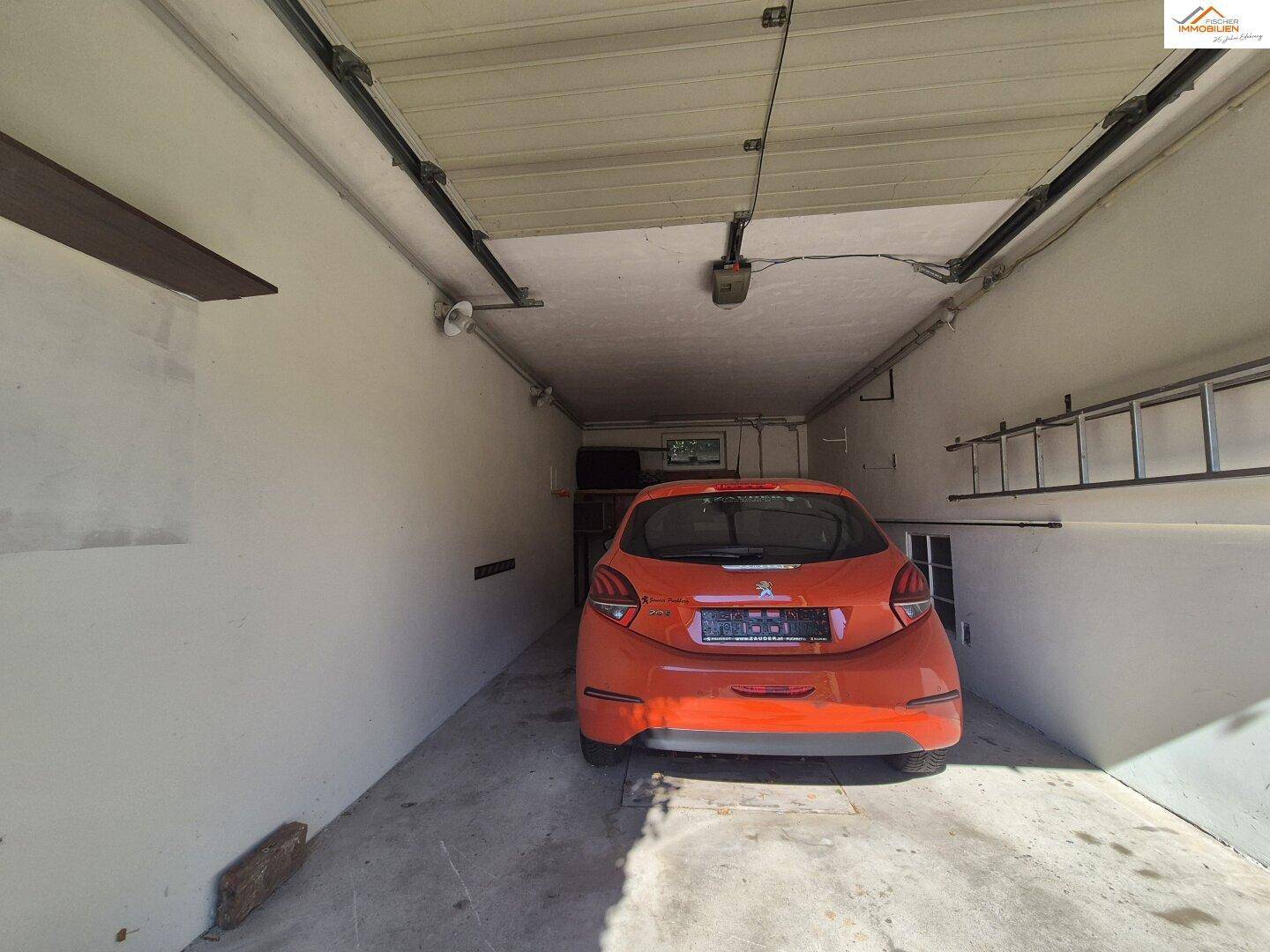 Geräumige Garage mit einem geparkten Auto und Stauraum an den Wänden.