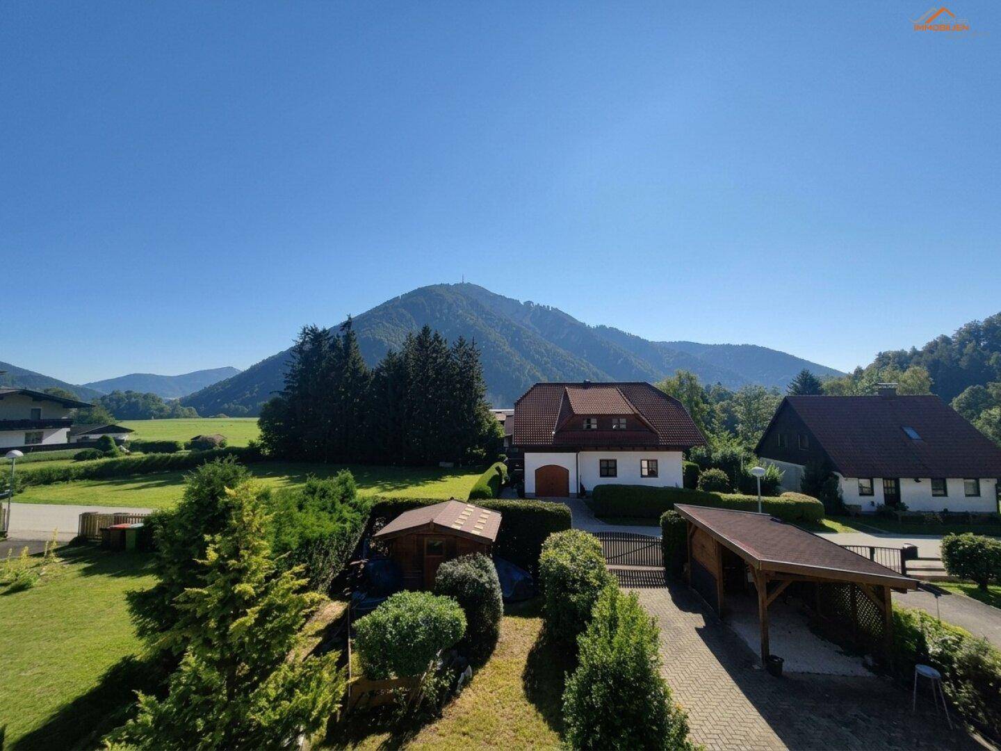 Weitläufiger Blick auf die ländliche Umgebung mit Bergen, grünen Wiesen und Einfamilienhäusern.
