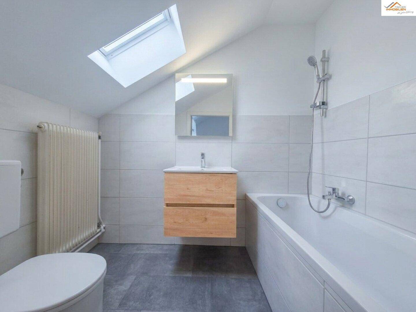 Modernes Badezimmer mit Dachfenster, Badewanne, schwebendem Waschtisch und Duschvorrichtung.