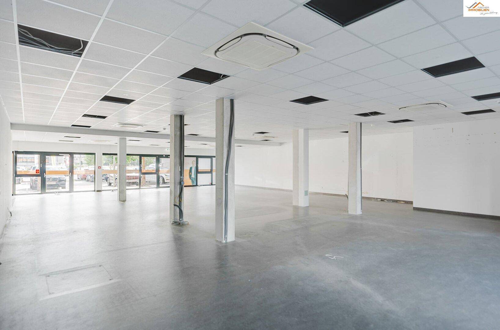 Großer, leerer Gewerberaum mit Betonboden, abgehängter Decke und Säulen, bereit für den Ausbau.
