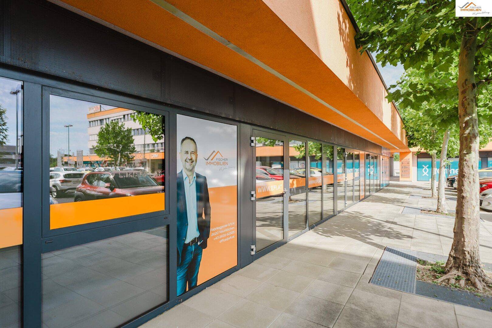 Fassade eines Geschäftsgebäudes mit großen Schaufenstern und einem Werbeplakat an der Front.