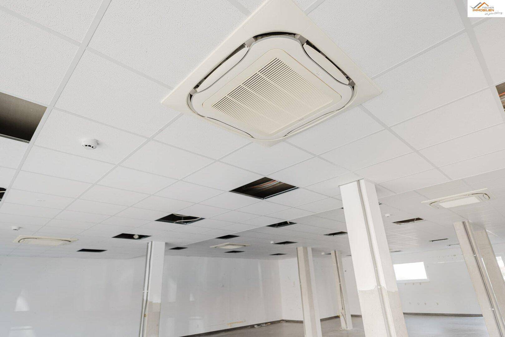 Deckenmontierte Klimaanlage in einem Gewerberaum mit abgehängter Decke und Beleuchtung.