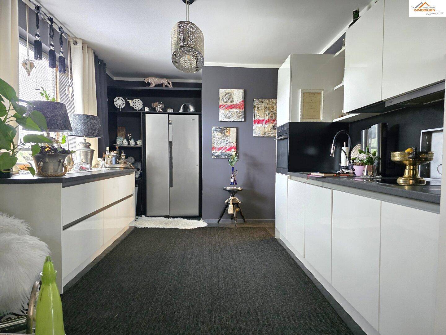 Moderne Küche mit weißen Hochglanzfronten, dunklen Arbeitsplatten und integrierten Geräten.