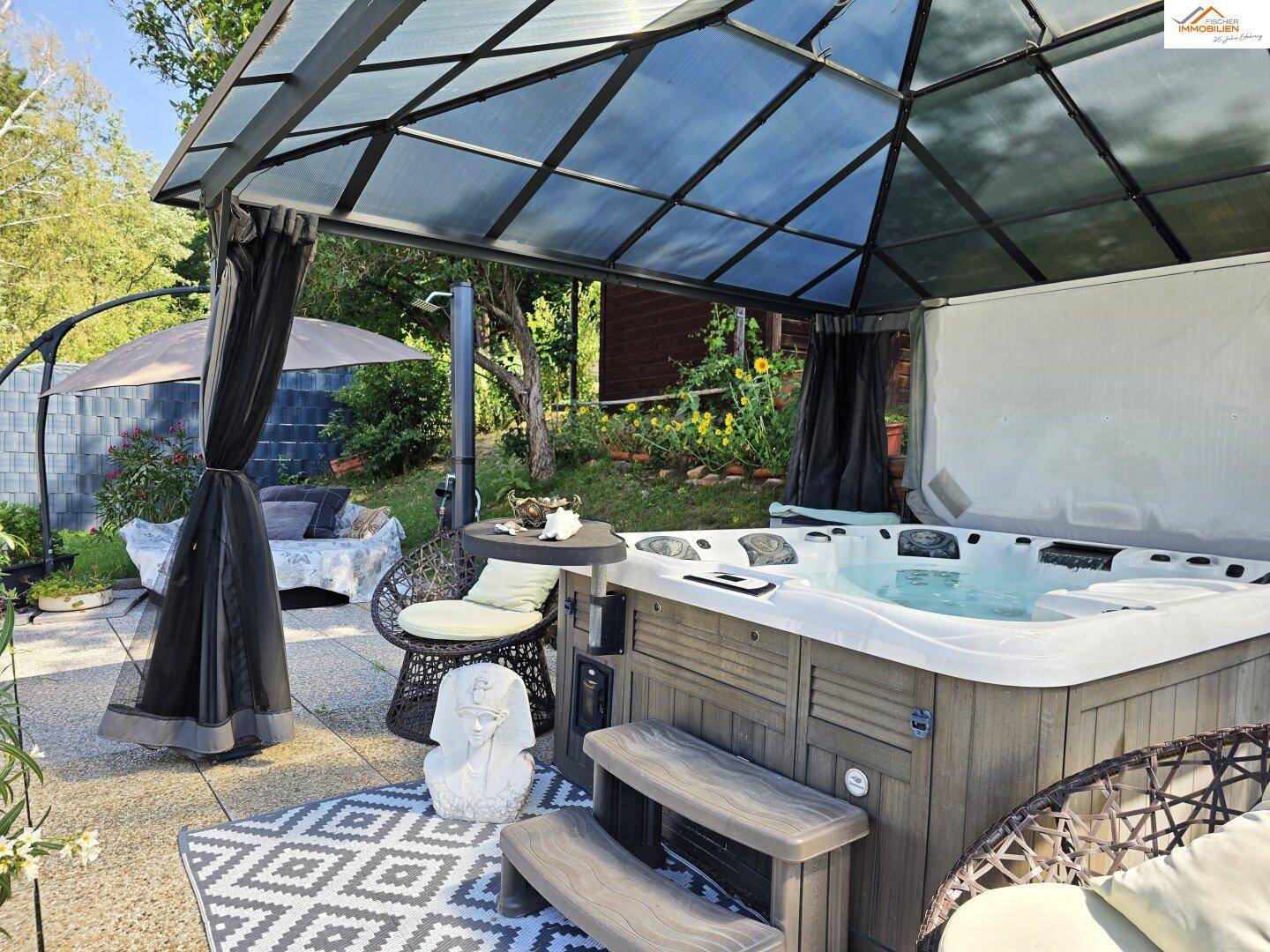 Entspannungsbereich auf der Terrasse mit großem Whirlpool unter einer Pergola.