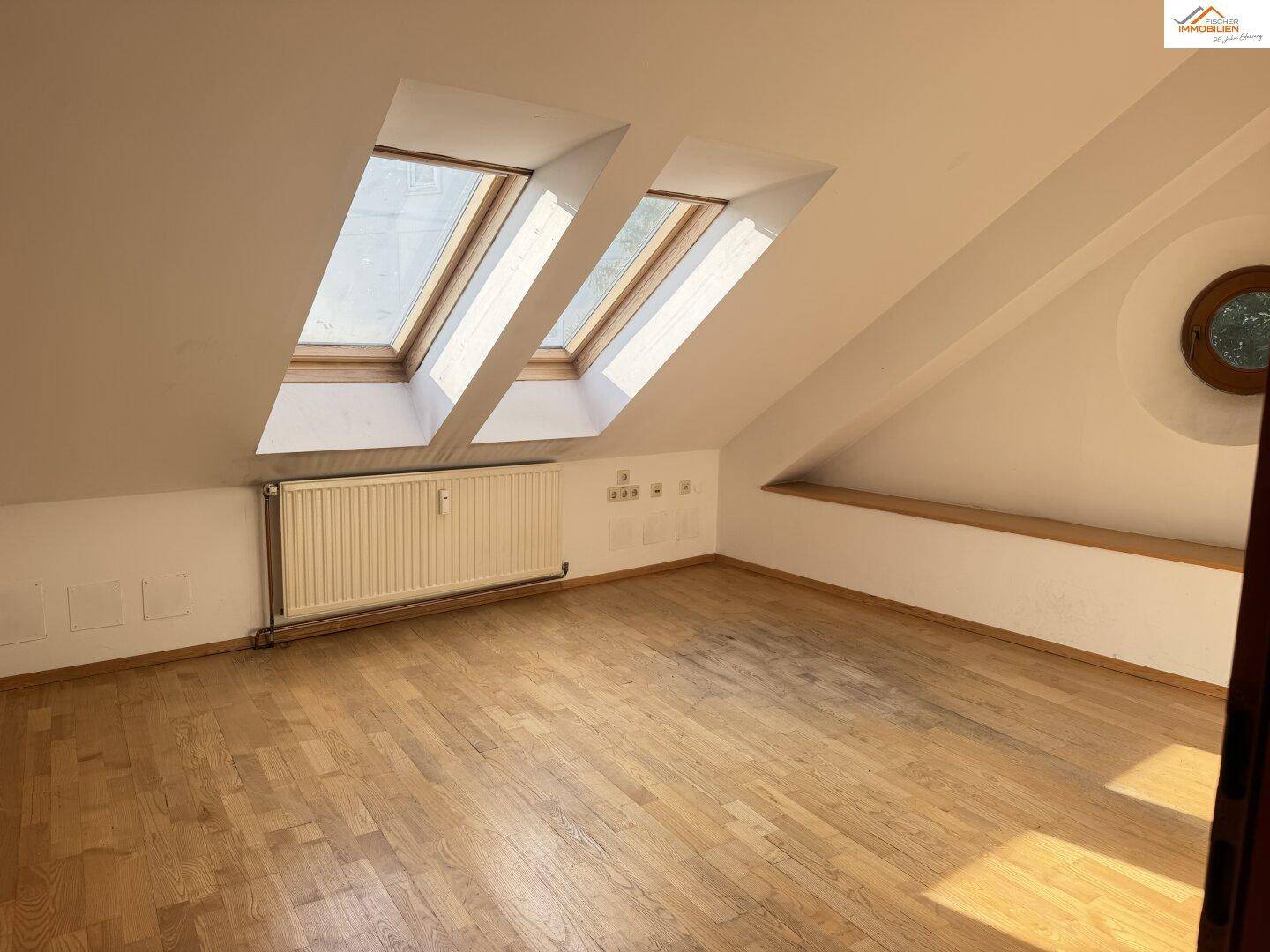 Heller Dachraum mit zwei Dachfenstern und Heizkörper, ideal für zukünftige Nutzung.