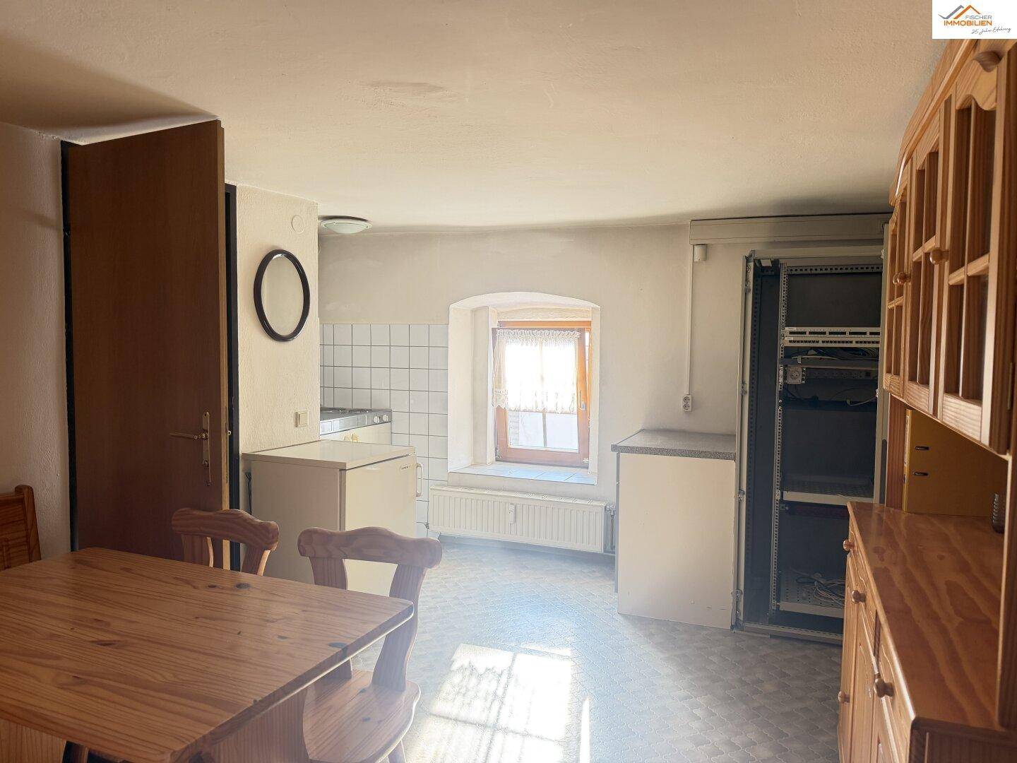 Rustikale Küche mit Holztisch, Einbauschränken und kleinem Fenster, bietet gemütlichen Charme.