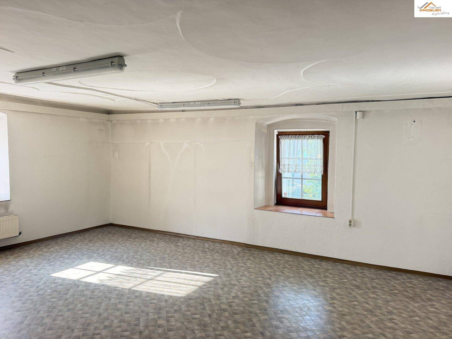 Geräumiger Raum mit gemustertem Boden und Fenster, bietet vielseitige Nutzungsmöglichkeiten.