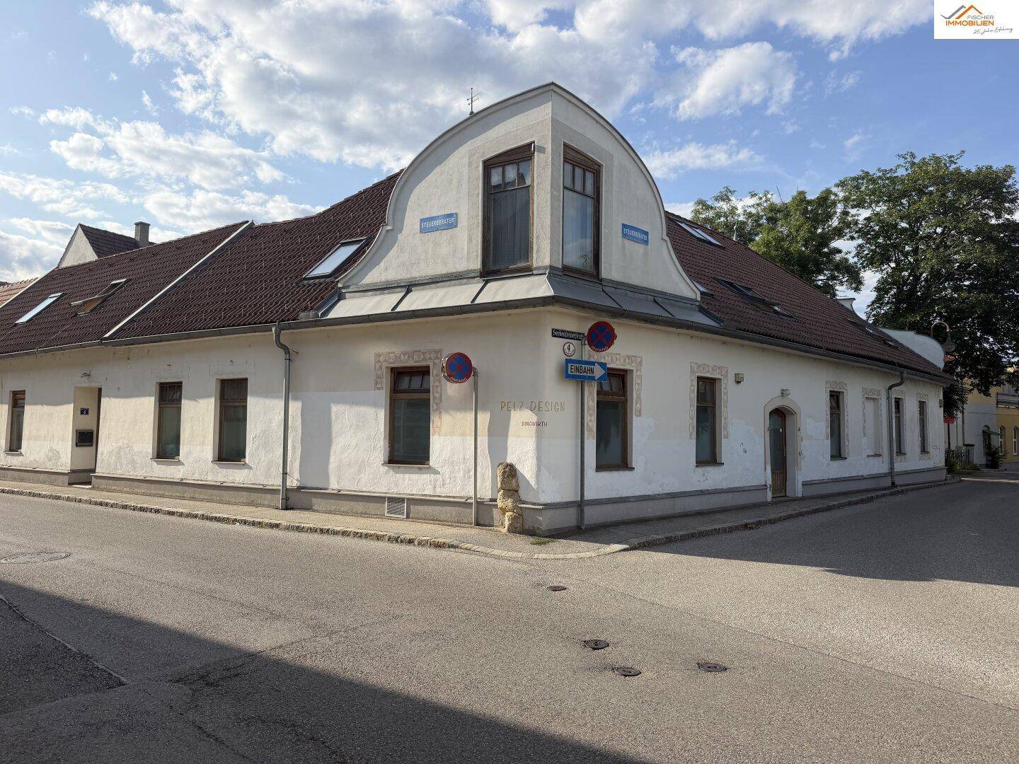 Historisches Eckgebäude mit Mansarddach und traditioneller Fassade an einer Straße.