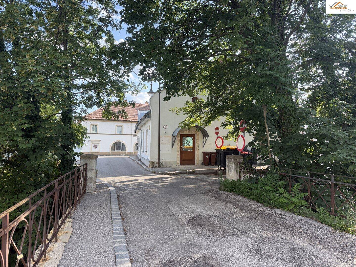Charmantes Gebäude umgeben von Bäumen, zugänglich über eine kleine Brücke.