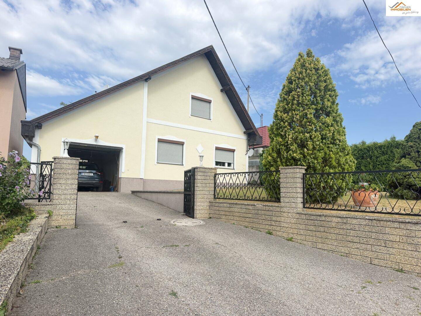 Einfamilienhaus mit Garagenzufahrt und gepflastertem Bereich vor dem Eingang.
