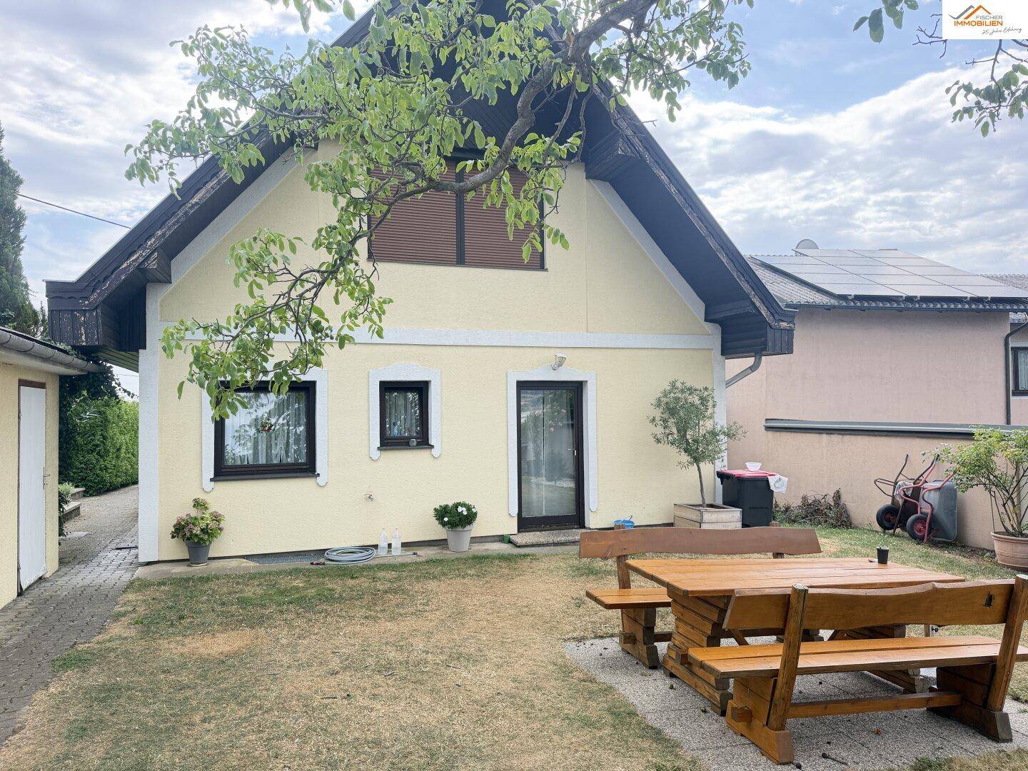Rückseite des Hauses mit Garten, Sitzgelegenheit und Baumbestand.
