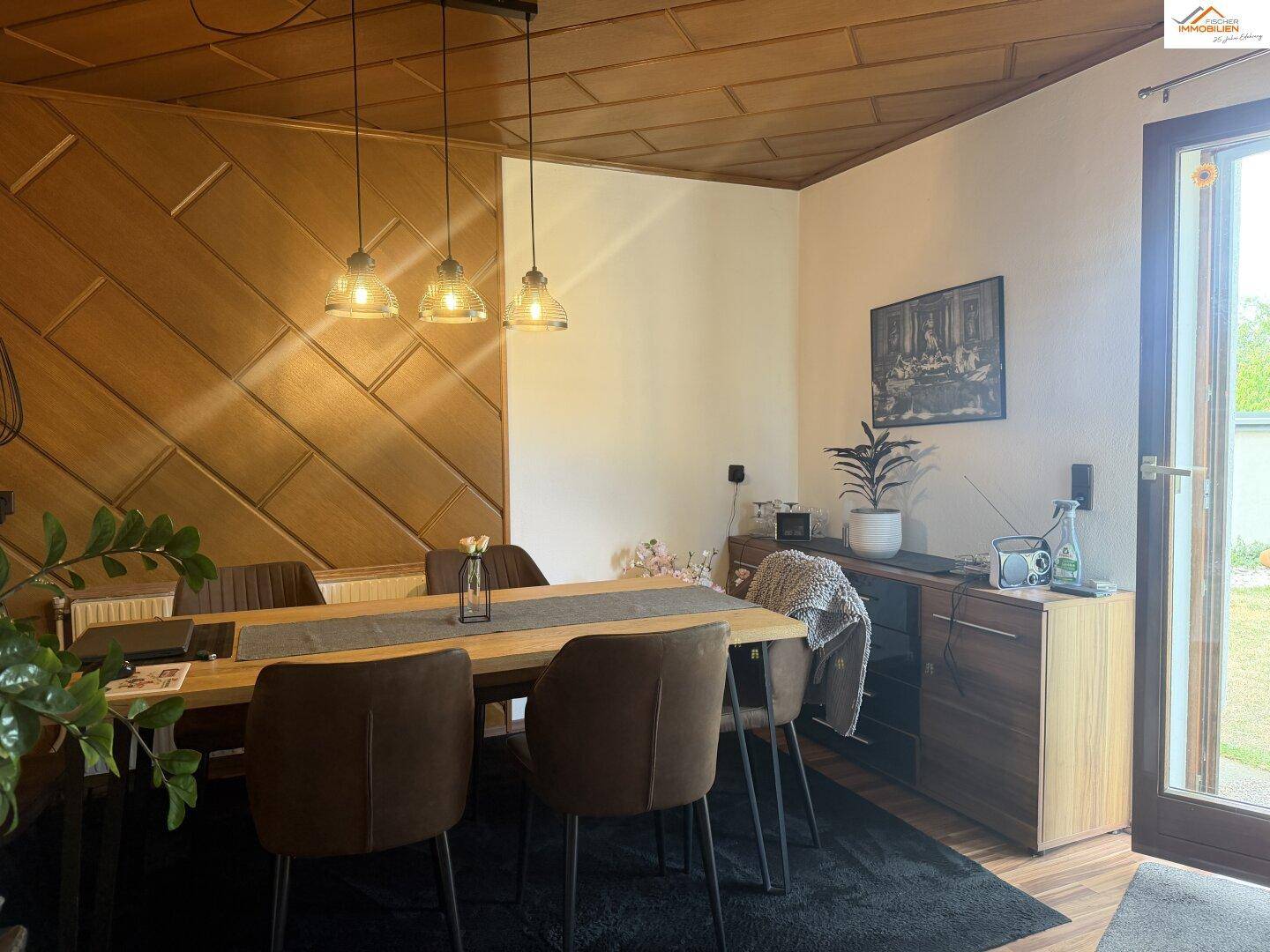 Gemütlicher Essbereich mit Holztisch, modernen Stühlen und Holzwandverkleidung.