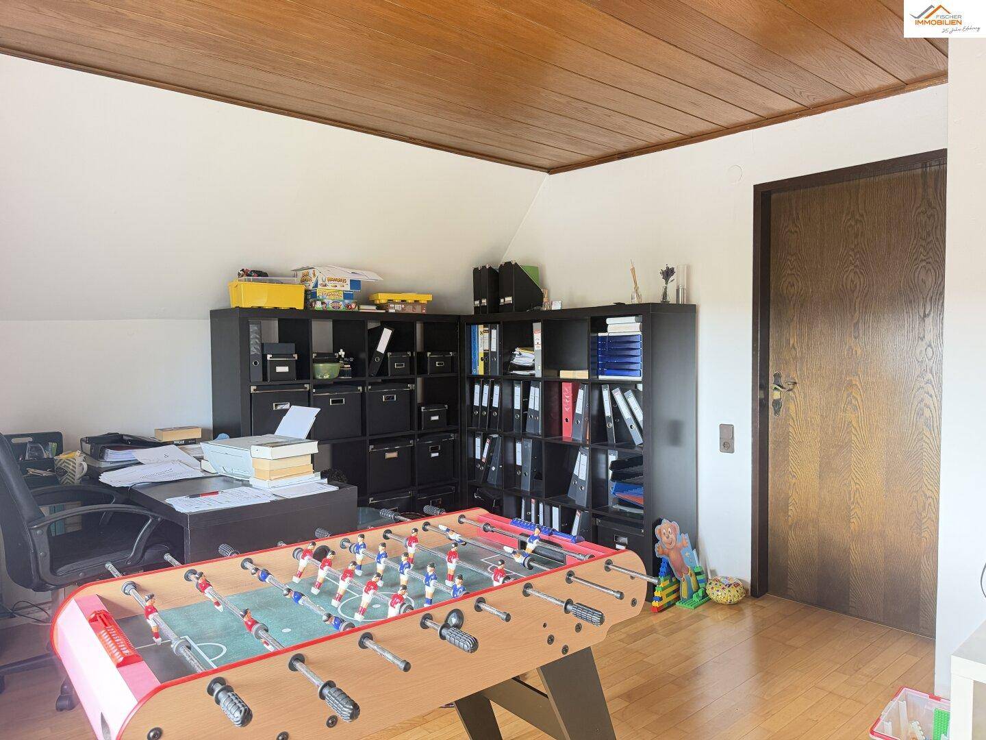 Arbeitszimmer im Dachgeschoss mit Schreibtisch, Regalen und Tischfußball.