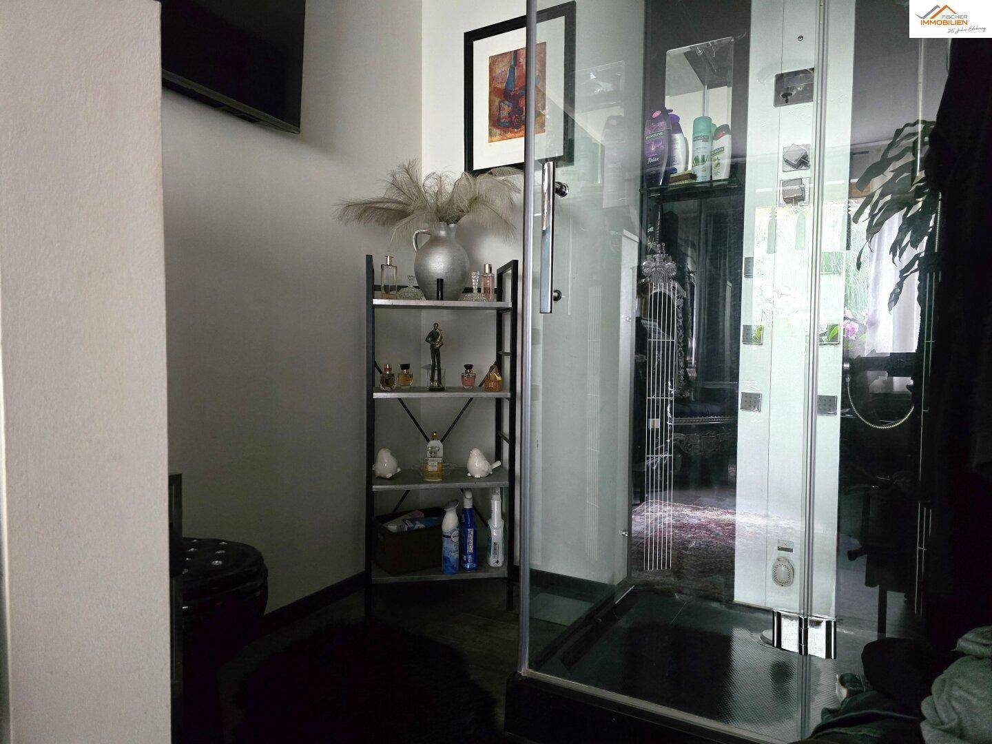 Modernes Badezimmer mit Glasduschkabine und minimalistischem Regal für Pflegeprodukte.