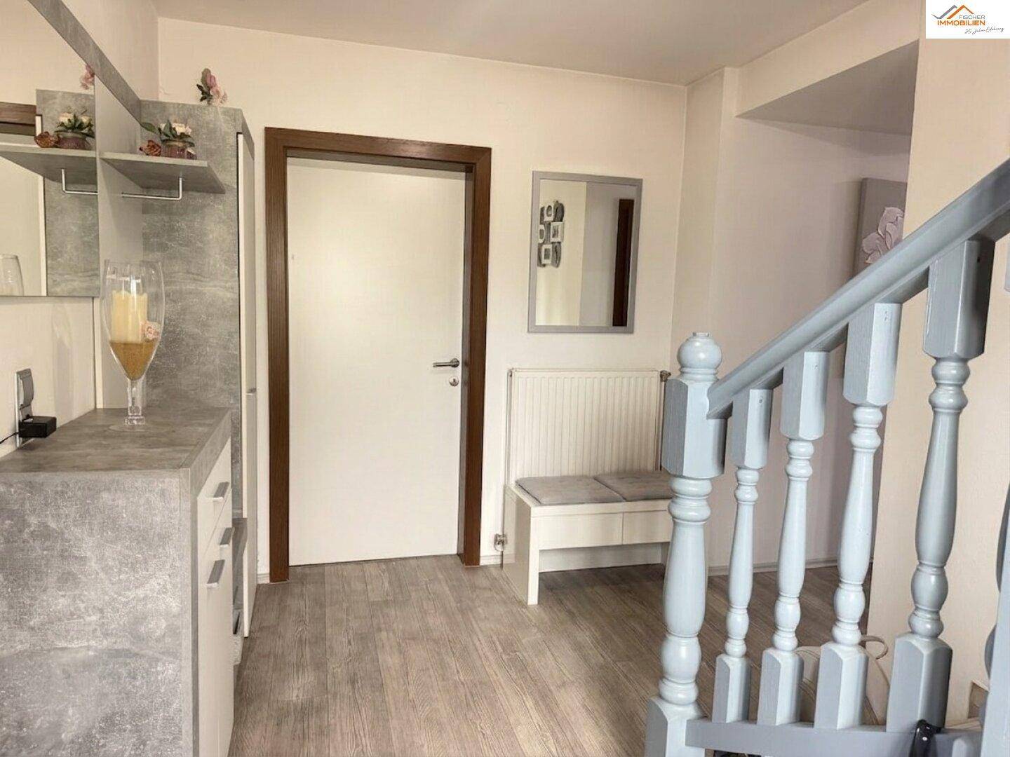 Heller Eingangsbereich mit Garderobe, Sitzbank und Treppenaufgang.