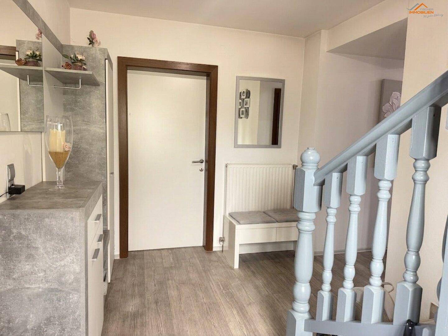 Heller Eingangsbereich mit Treppe, Garderobe und Sitzbank, ausgestattet mit Laminatboden.