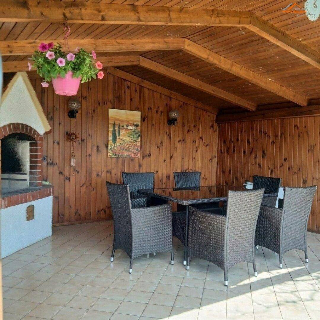 Überdachte Terrasse mit Holzwänden, Fliesenboden und integriertem Grillbereich für gesellige Abende.
