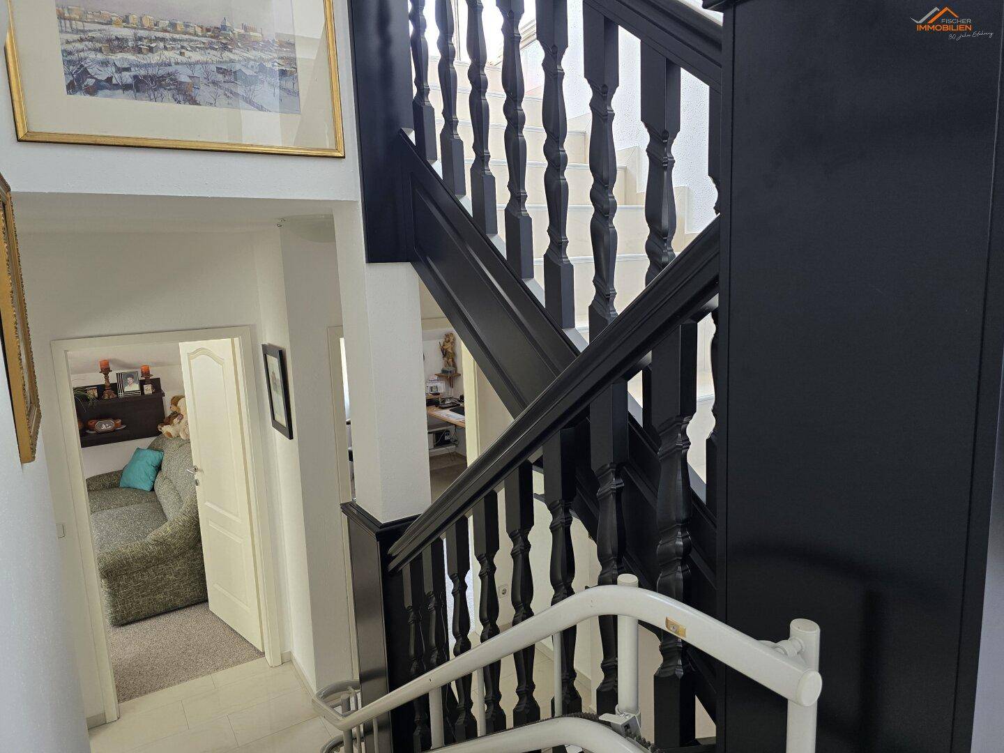 Dunkle Holztreppe mit elegantem Geländer, die verschiedene Ebenen des Hauses verbindet.
