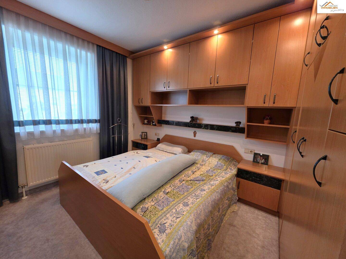 Schlafzimmer mit großem Bett, Einbauschränken und Fenster, bietet viel Stauraum.