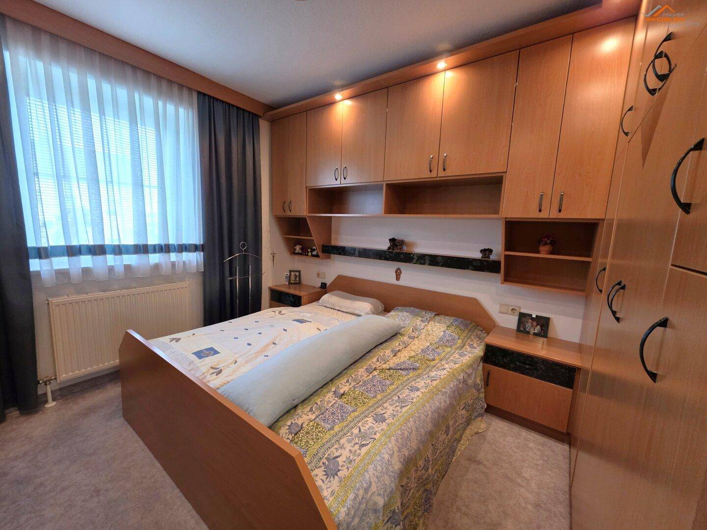 Schlafzimmer mit großem Bett und integrierten Holzschränken, die viel Stauraum bieten.
