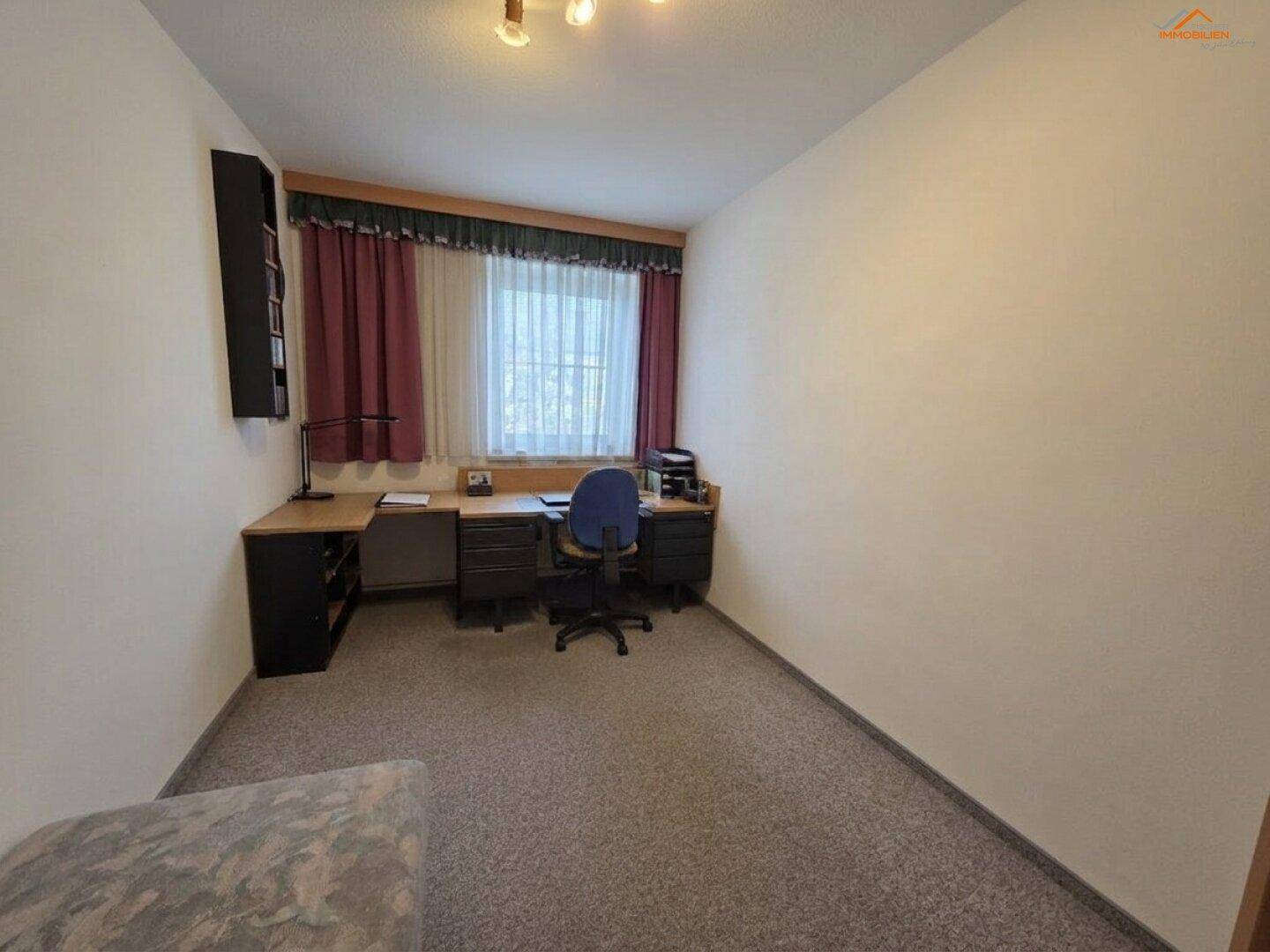 Ruhiges Arbeitszimmer mit Teppichboden, Schreibtisch und Fenster, ideal für Home-Office.