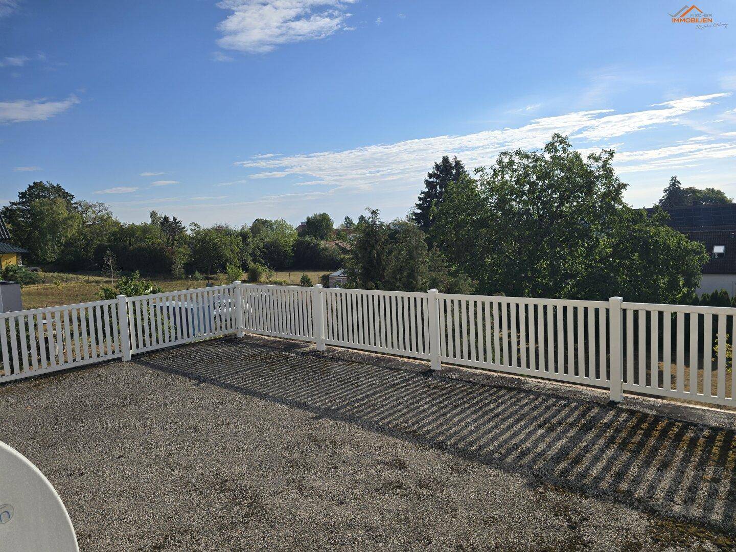 Weitläufige Dachterrasse mit Kiesboden und weißem Geländer, bietet einen Panoramablick.