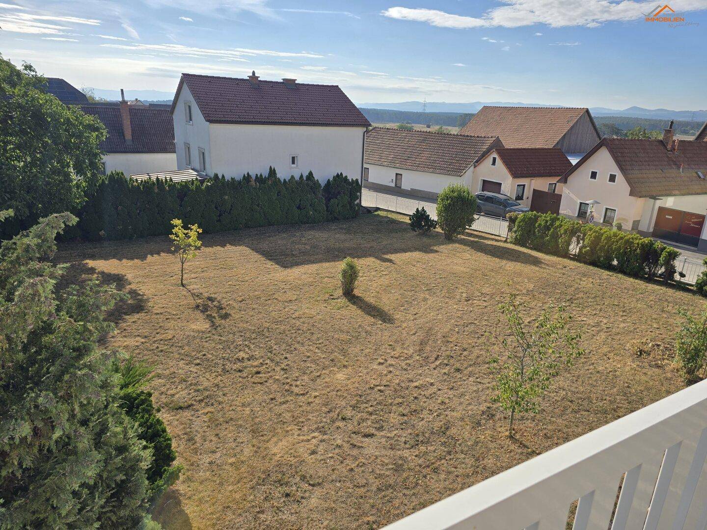 Großer Gartenbereich mit Rasen und Blick auf die umliegende Landschaft und Häuser.