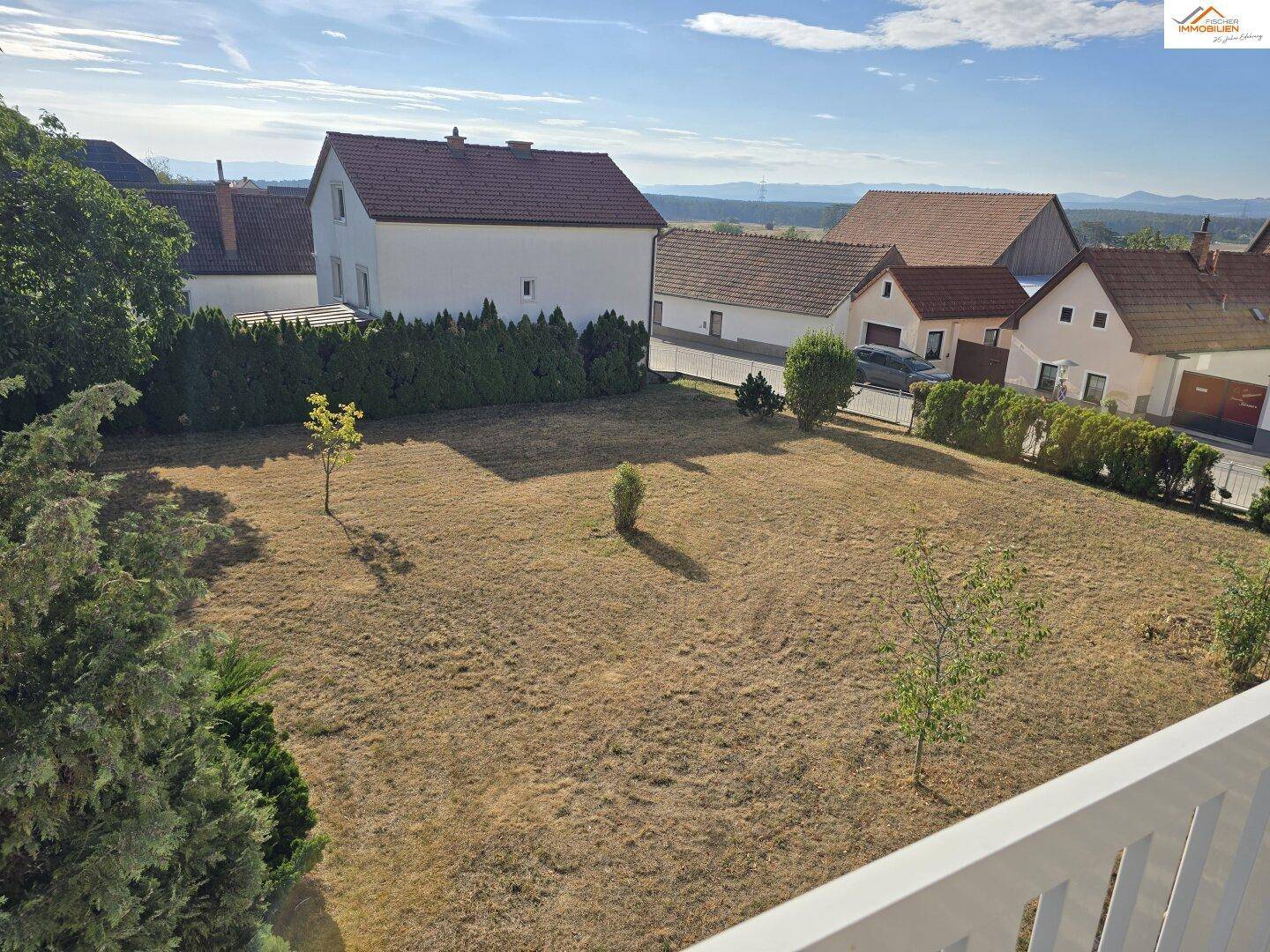 Blick von oben auf den weitläufigen Gartenbereich mit Rasen und angrenzenden Häusern.