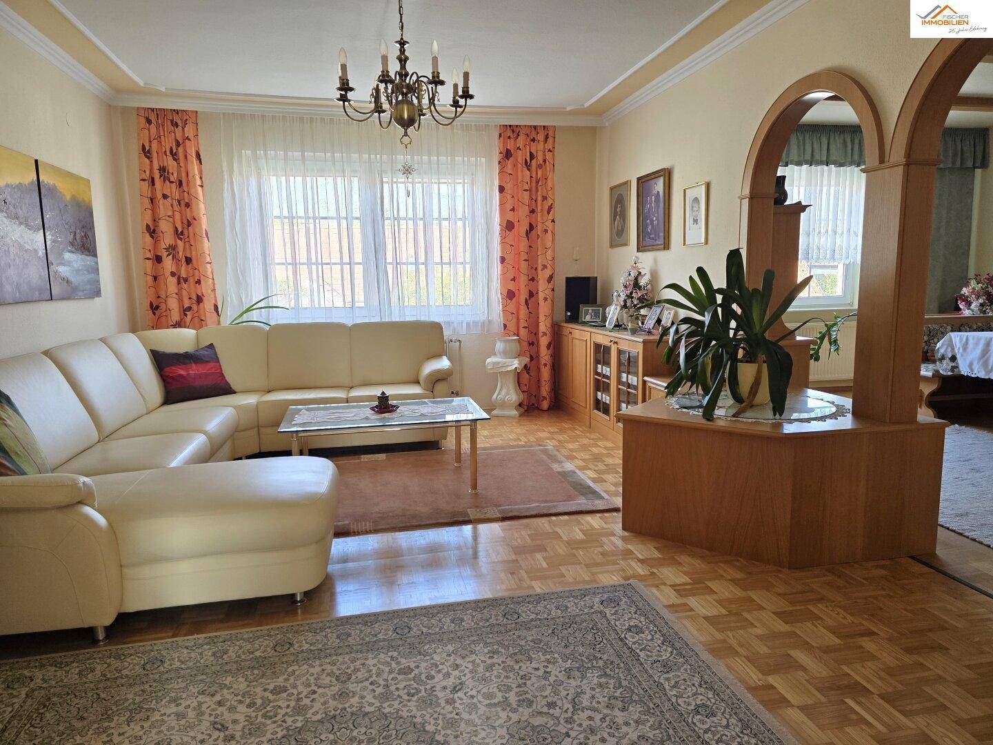 Gemütliches Wohnzimmer mit Ecksofa, Parkettboden und traditionellen Holzelementen.
