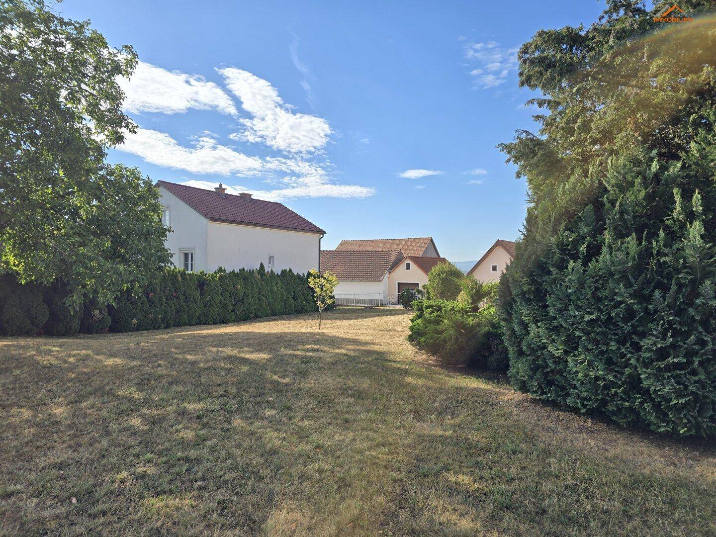 Großer Gartenbereich mit Rasen und Hecken, umgeben von weiteren Wohnhäusern in ländlicher Umgebung.
