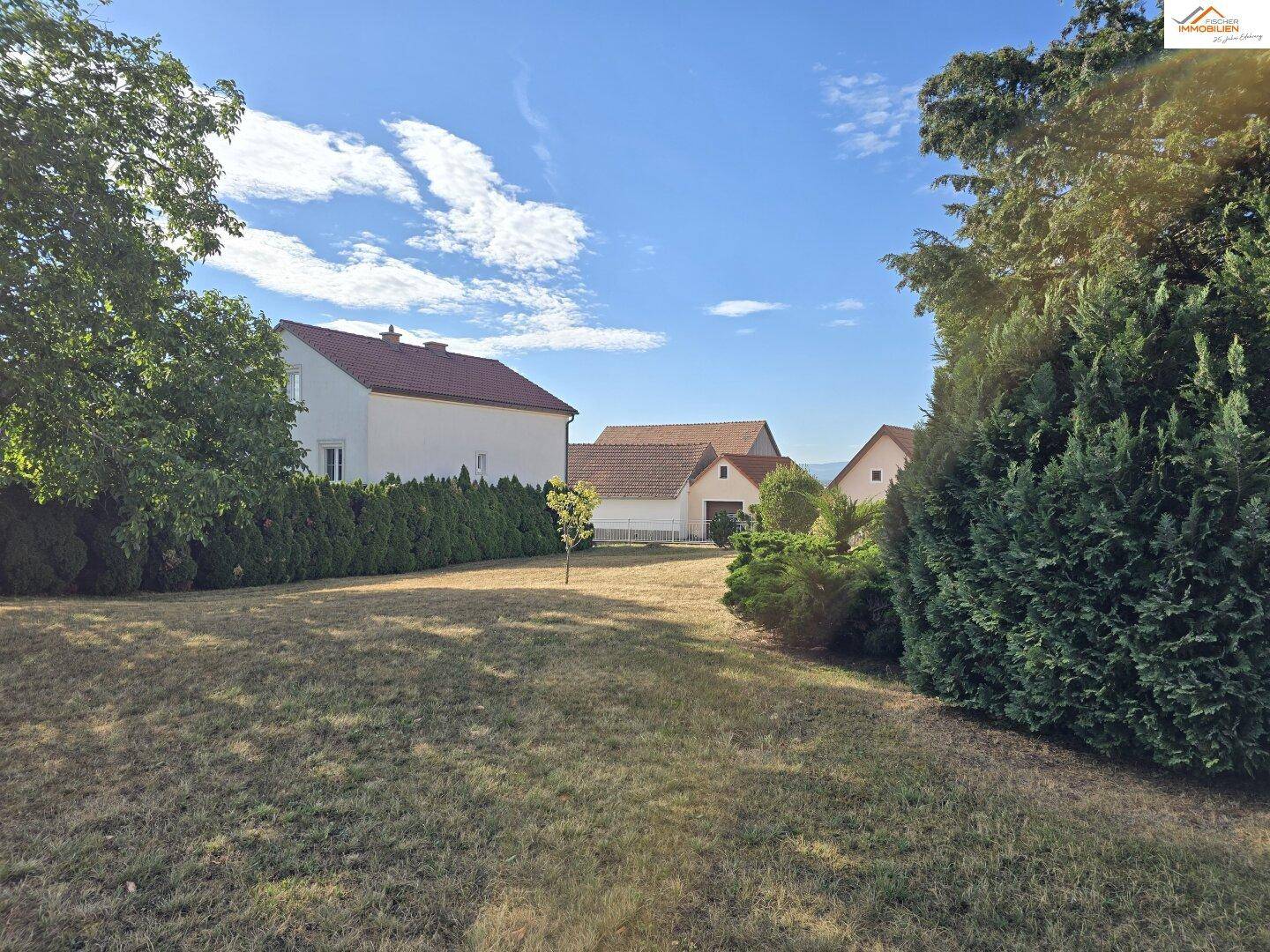 Weitläufiger Gartenbereich mit Bäumen und Hecken, bietet Privatsphäre und Blick auf Nachbarhäuser.