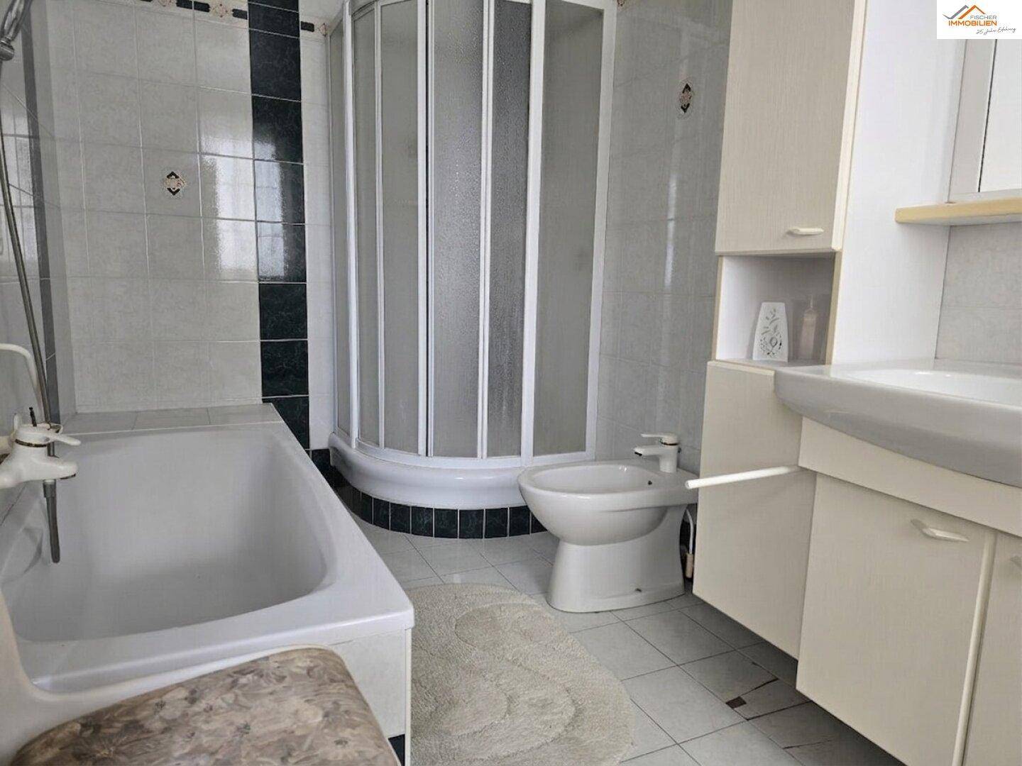 Badezimmer mit Badewanne, Duschkabine, Bidet und Fliesen in Hell- und Dunkelgrün.