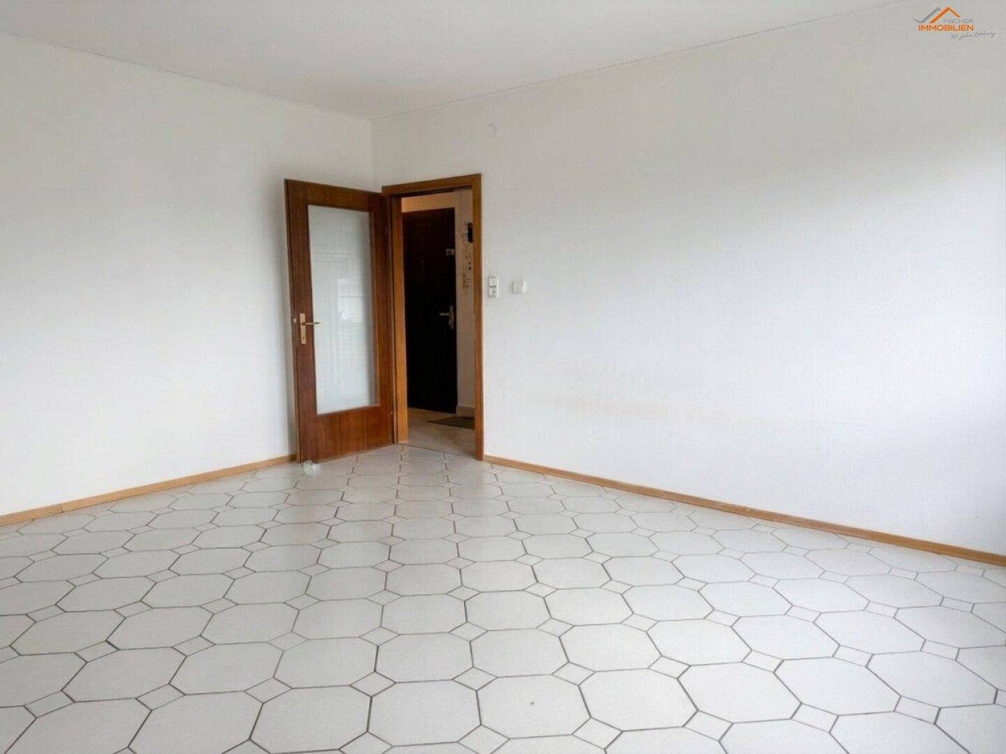 Geräumiges Zimmer mit auffälligem sechseckigem Fliesenboden und einer Holztür mit Glaseinsatz.