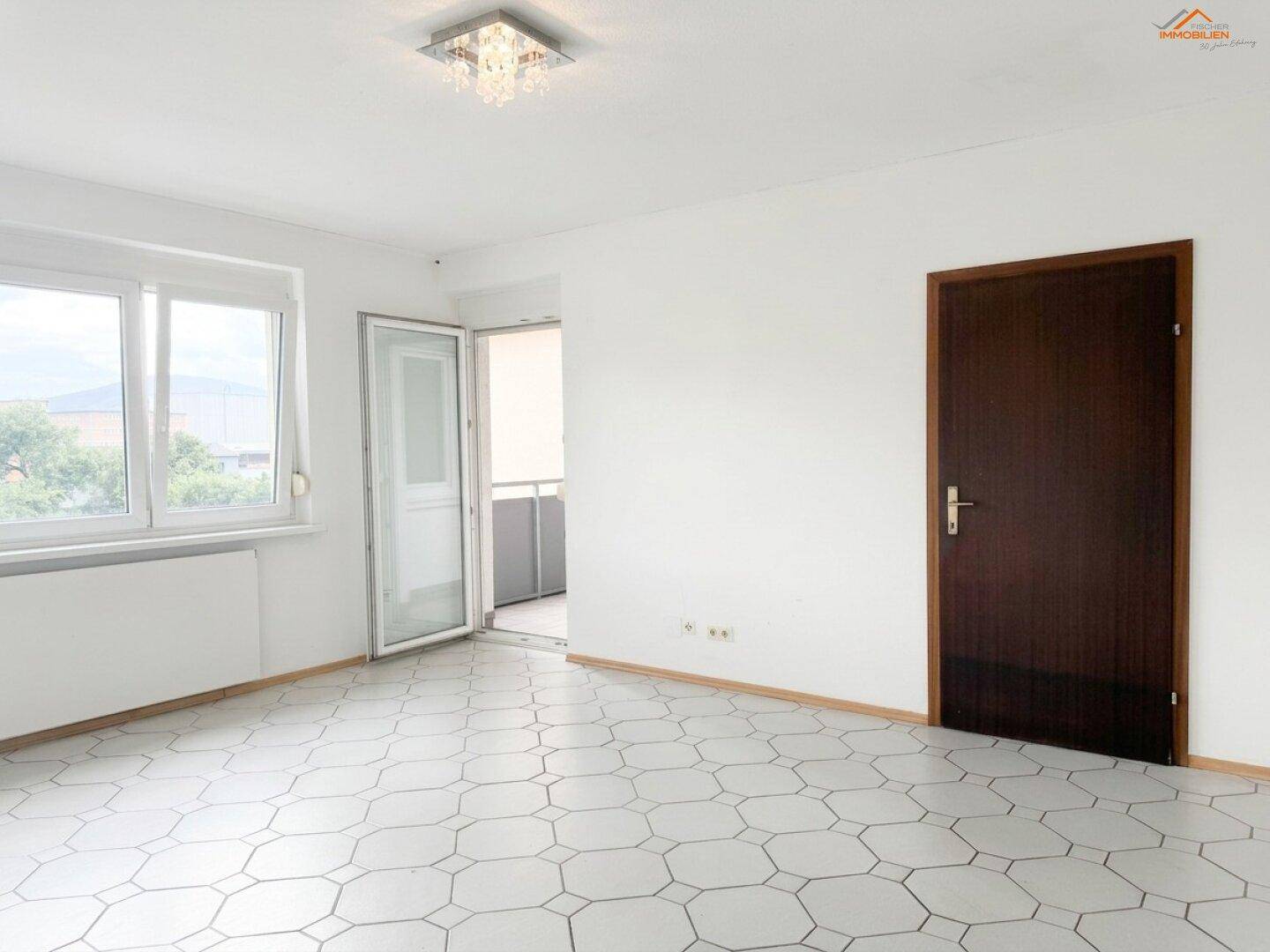 Heller Wohnraum mit Fliesenboden und Zugang zu einem Balkon, der viel natürliches Licht bietet.