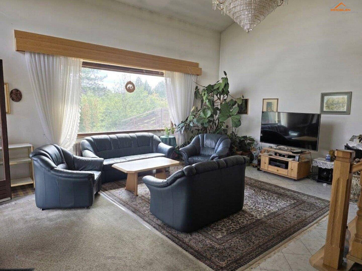 Geräumiges Wohnzimmer mit hohen Decken, großen Fenstern und traditionellen Möbeln.