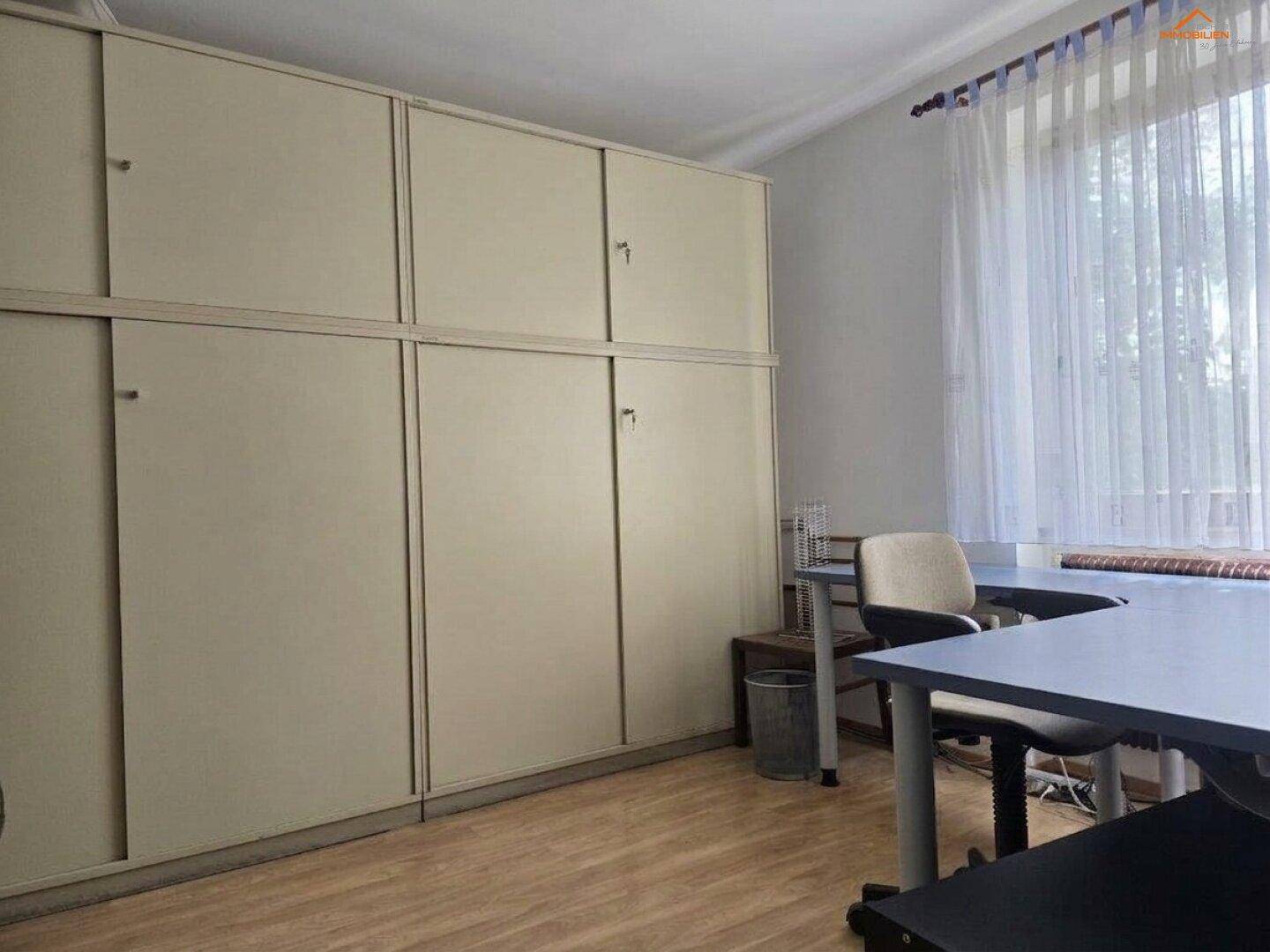 Funktionales Büro mit großen Einbauschränken und Fenster für Tageslicht.