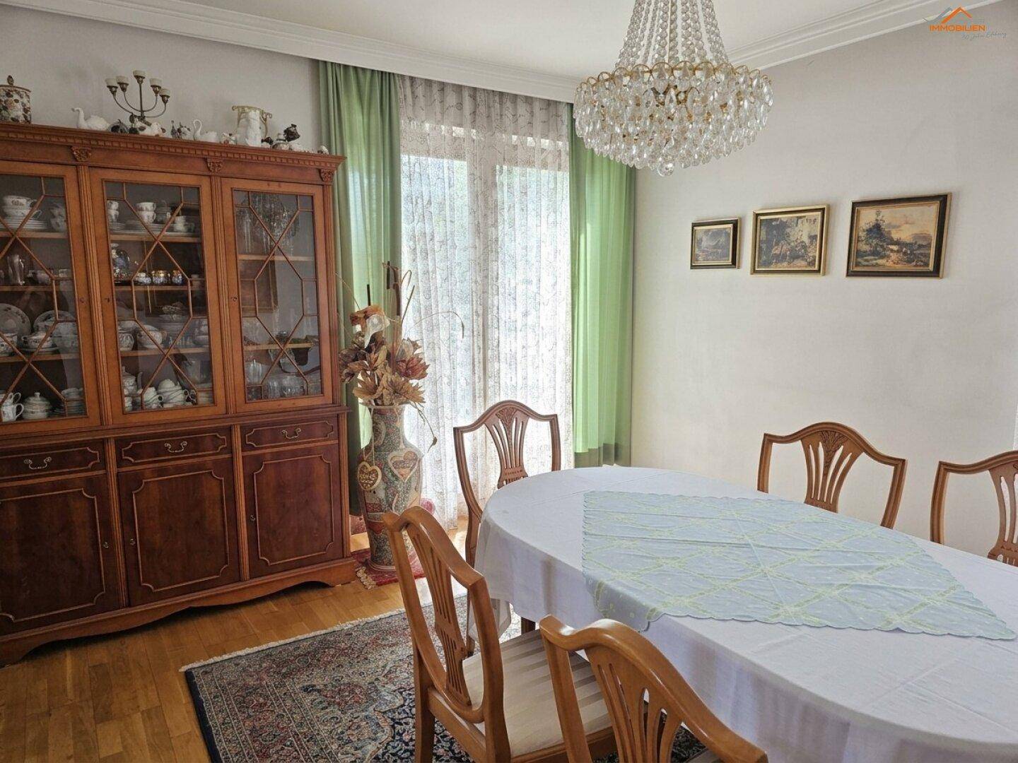 Klassisches Esszimmer mit Holztisch, Stühlen und einem großen Kronleuchter.