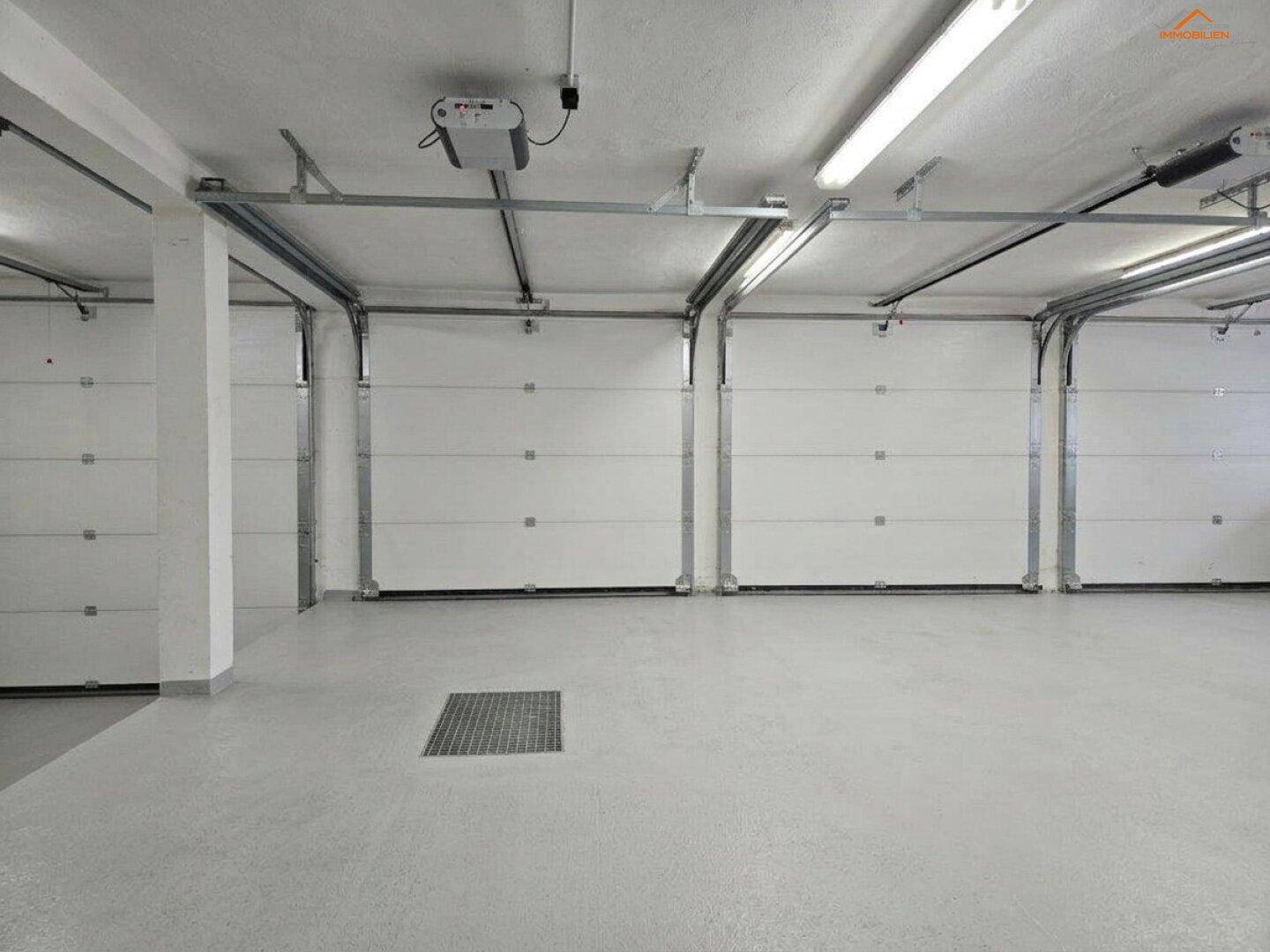 Geräumige Tiefgarage mit mehreren Sektionaltoren und hellem Betonboden, ideal für Fahrzeuge.
