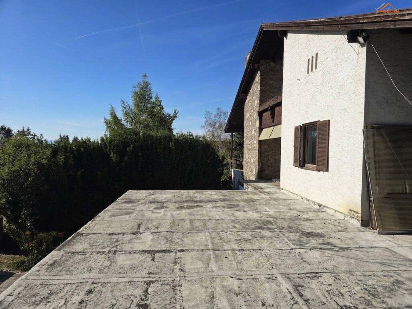Große, unfertige Betonfläche, die als zukünftige Dachterrasse oder Balkon dienen könnte, mit Blick ins Grüne.