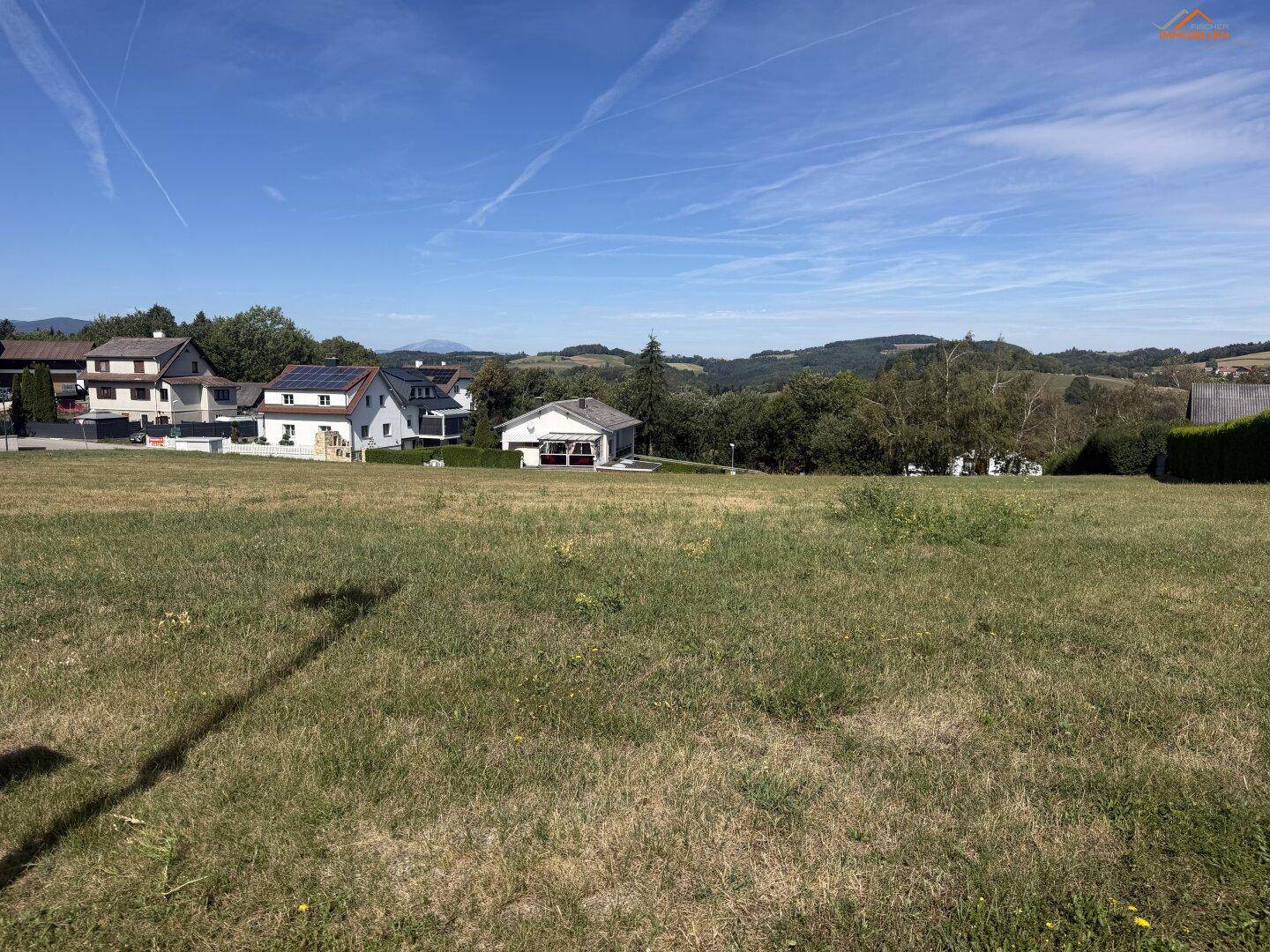 Offenes Grundstück mit weitem Blick über die Landschaft und angrenzende Wohnbebauung.
