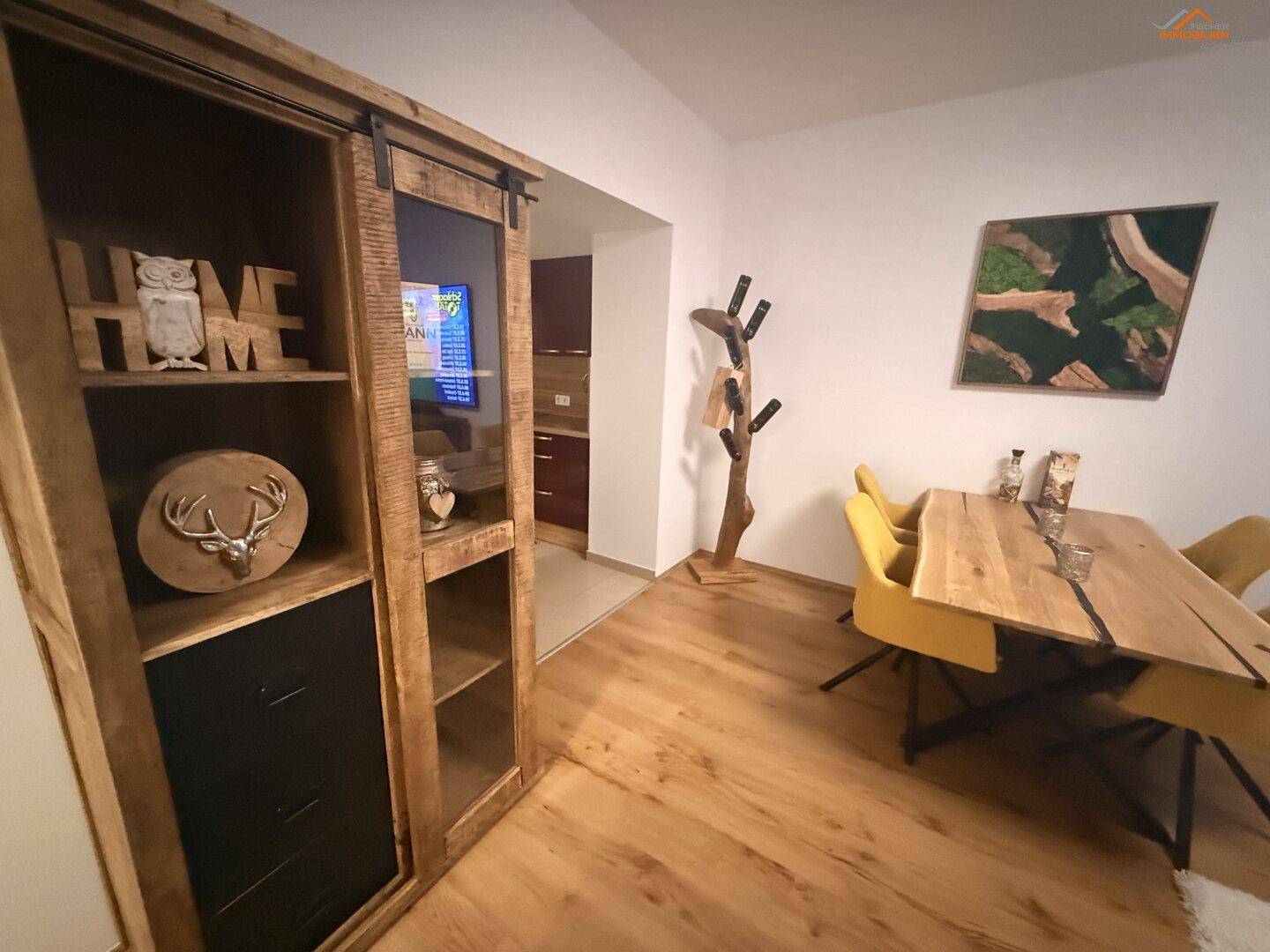 Essbereich mit Holztisch und gelben Stühlen, angrenzend an einen dekorativen Holzschrank.