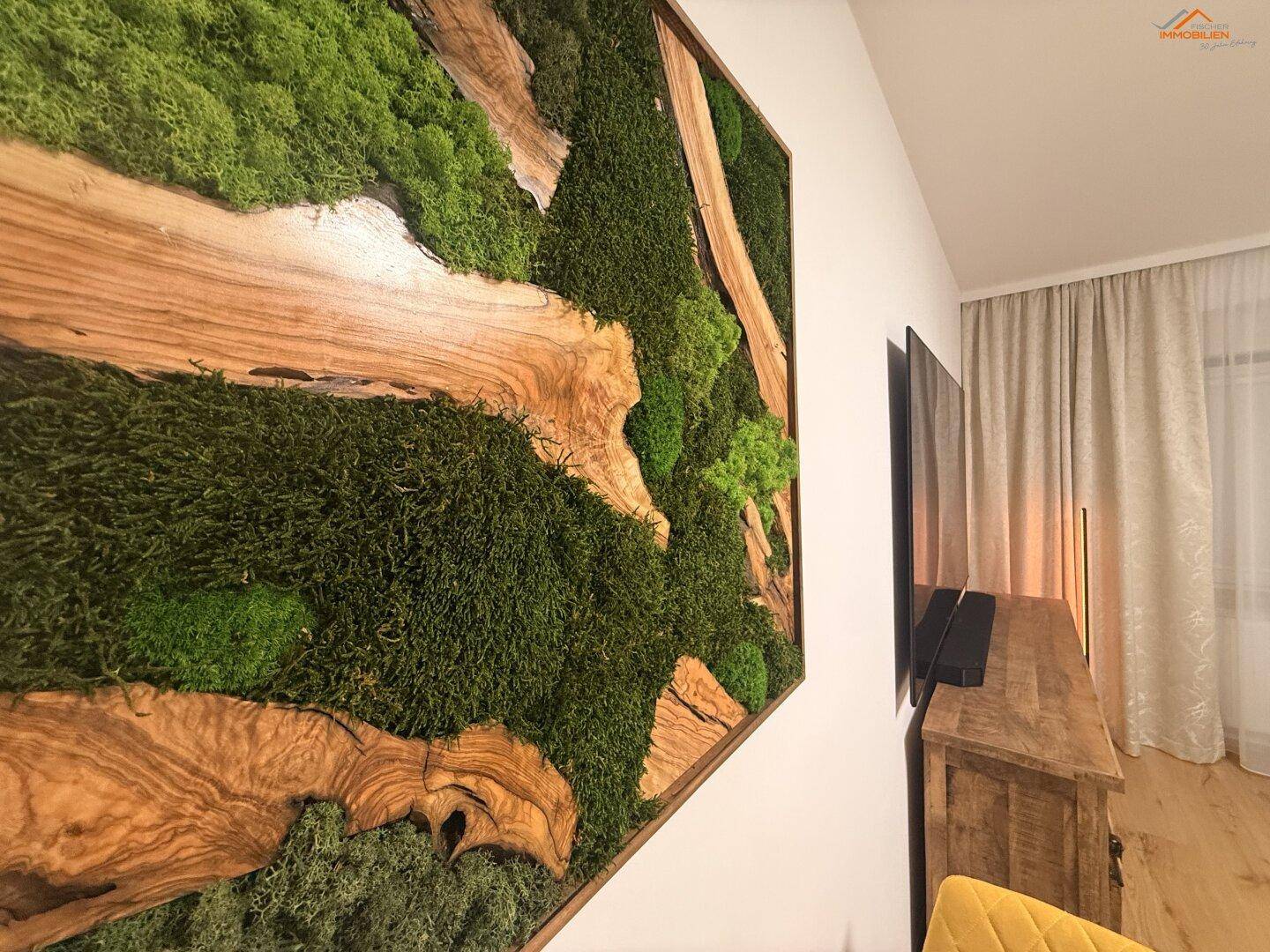 Detailansicht eines modernen Wandbildes aus Moos und Holz im Wohnbereich.