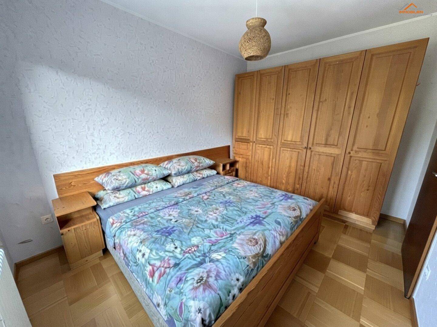 Schlafzimmer mit Holzbett, passenden Nachttischen und einem großen, eingebauten Holzschrank.