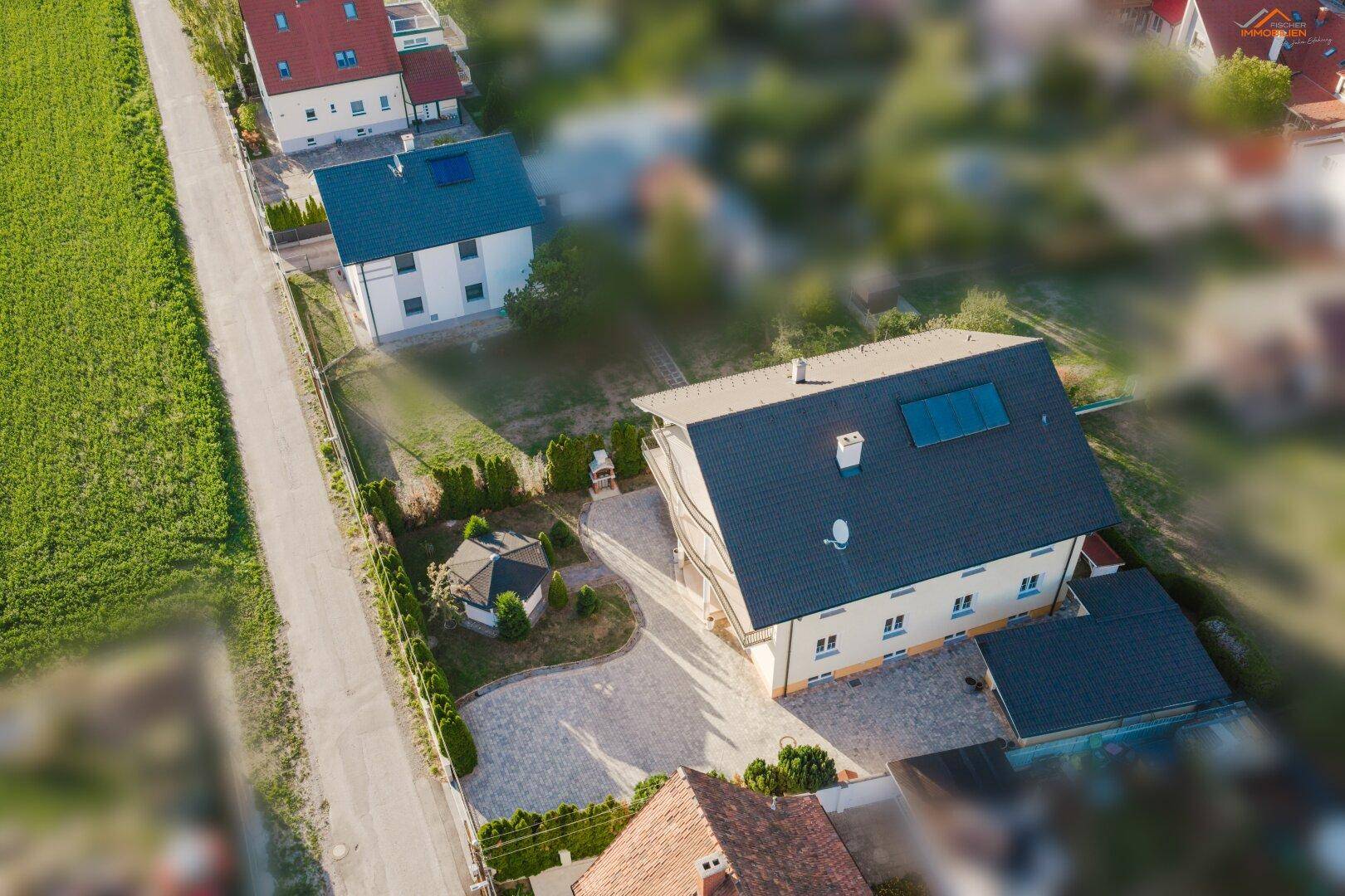 Luftaufnahme eines Einfamilienhauses mit gepflasterter Auffahrt und gepflegtem Gartenbereich.