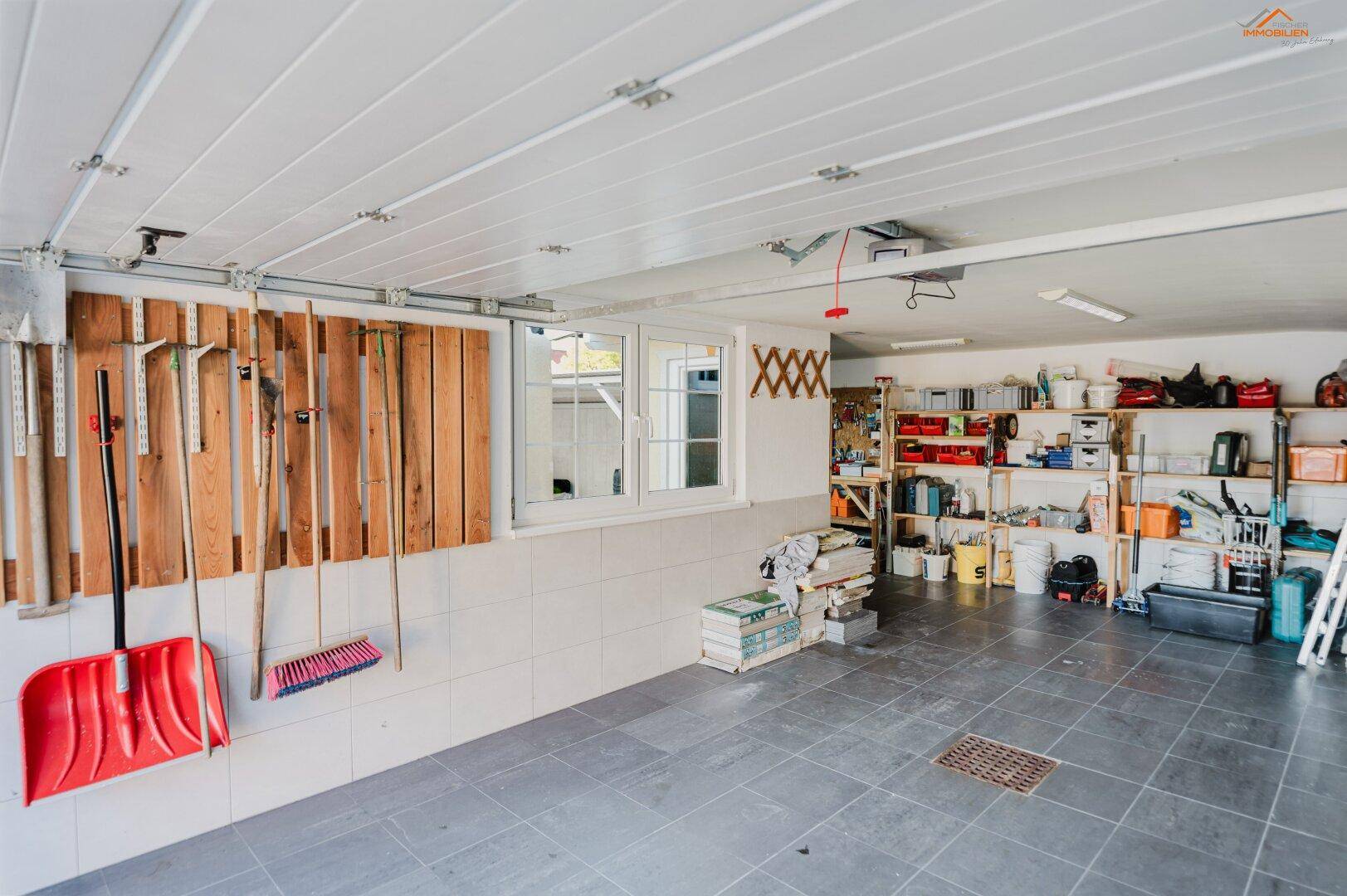 Geräumige Garage mit Werkzeugen, Regalen und einem Fenster, auch als Abstellraum nutzbar.